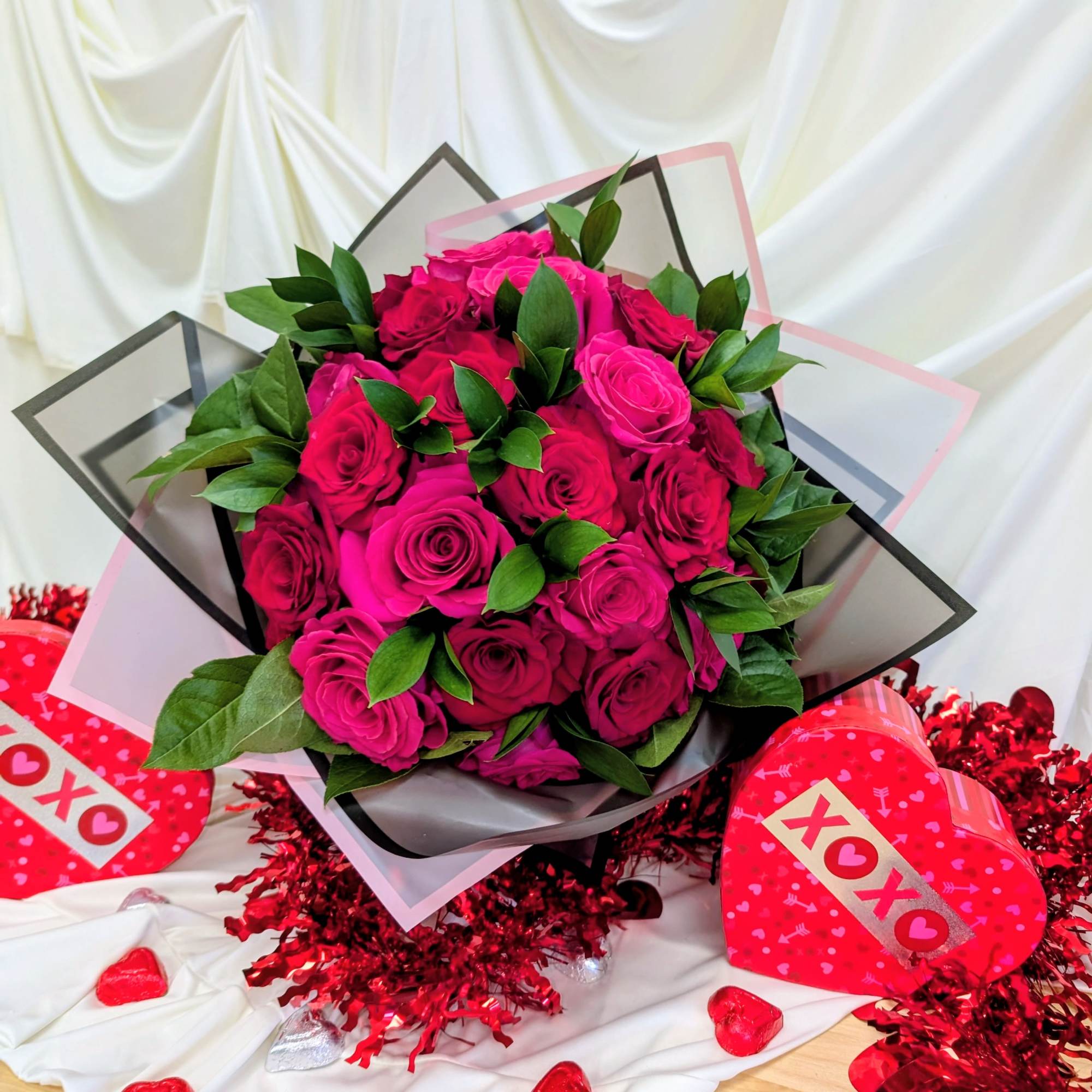 Bouquet of hot pink roses with green leaves, surrounded by heart decorations