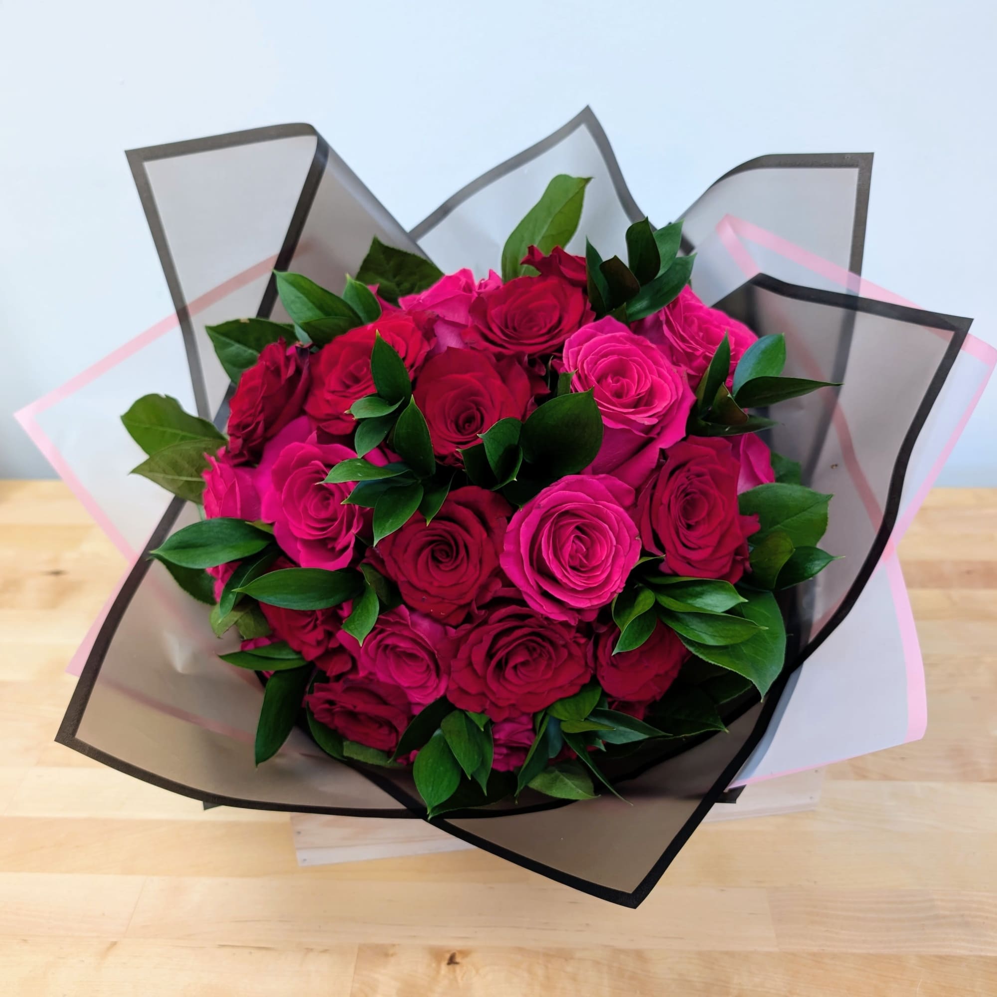 Bouquet of pink and red roses wrapped in black-edged paper