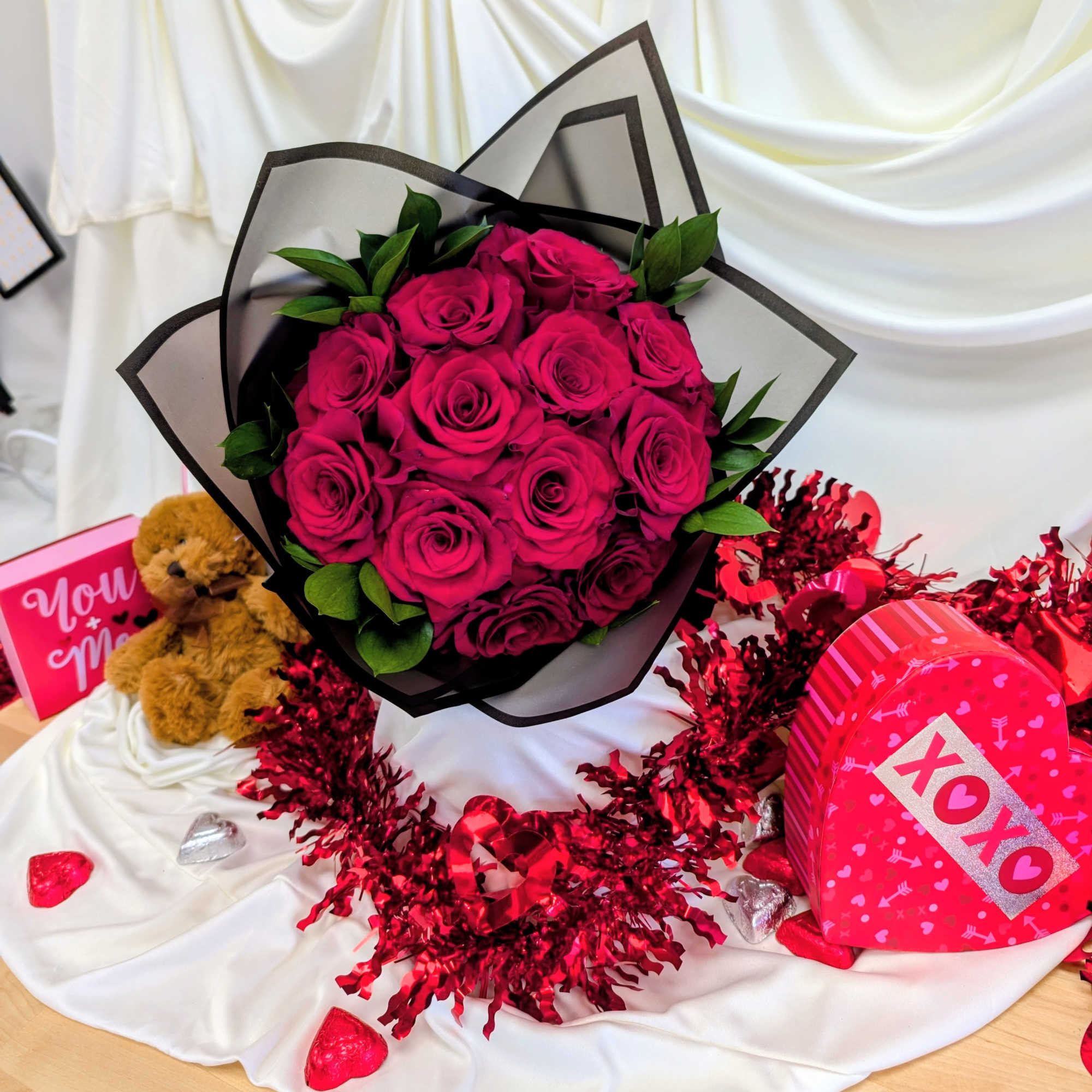 Bouquet of hot pink roses with a teddy bear and heart-shaped gift boxes