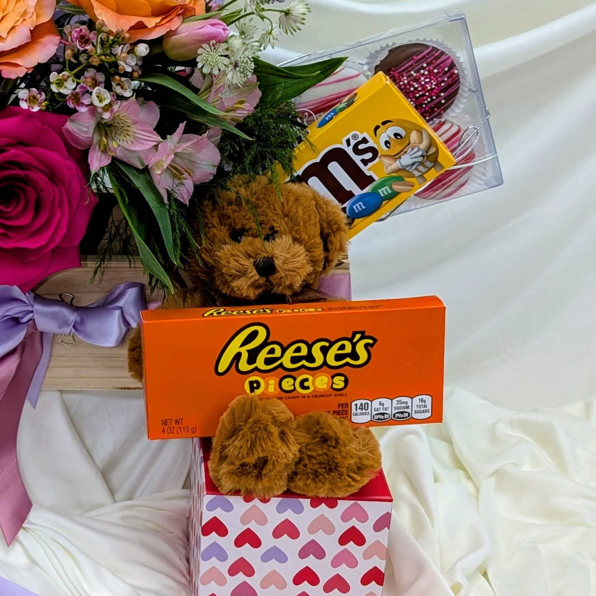 Flower arrangement with teddy bears and candy boxes in gift packaging