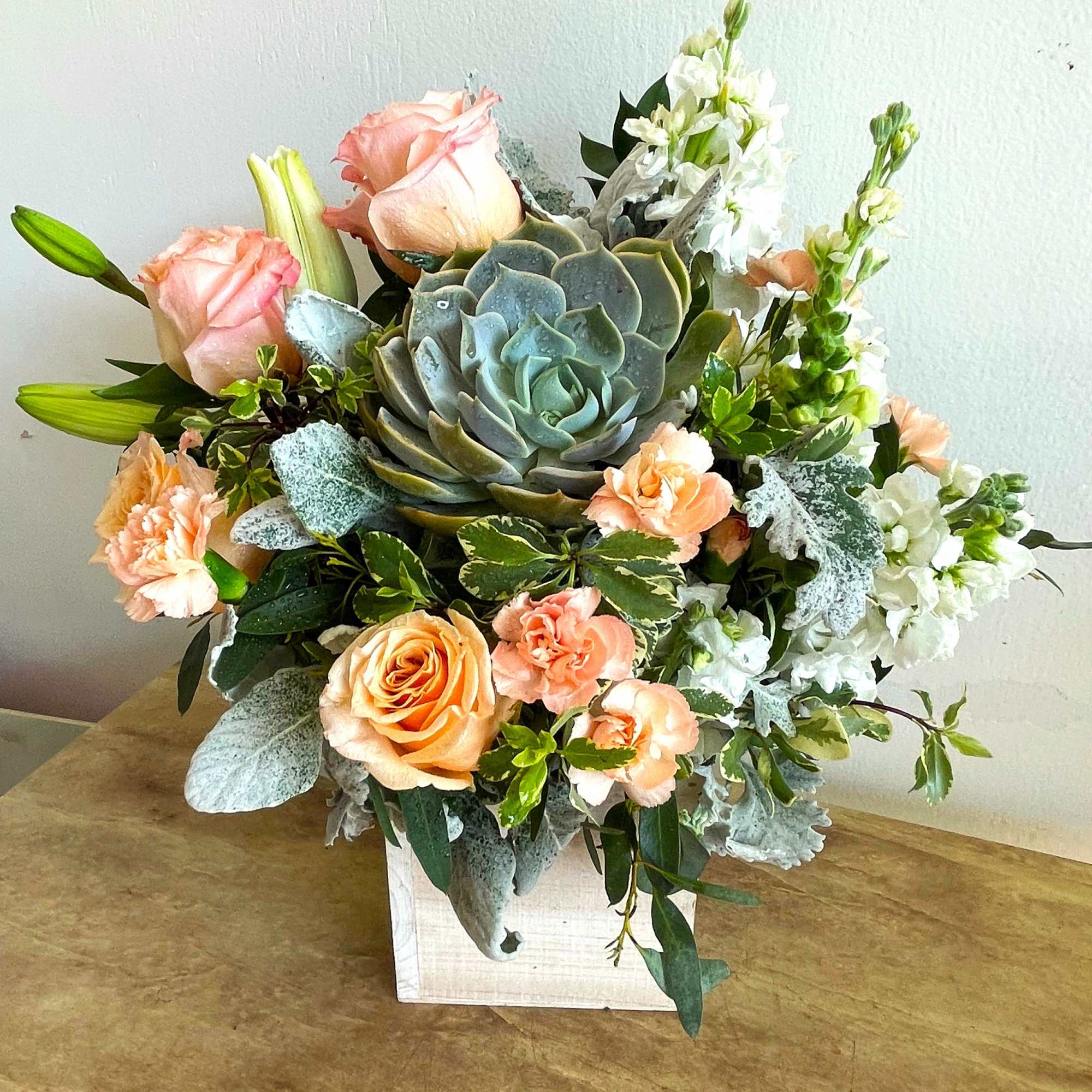 Peaceful yet energizing, this unforgettable arrangement of desert-hued blooms and succulents in