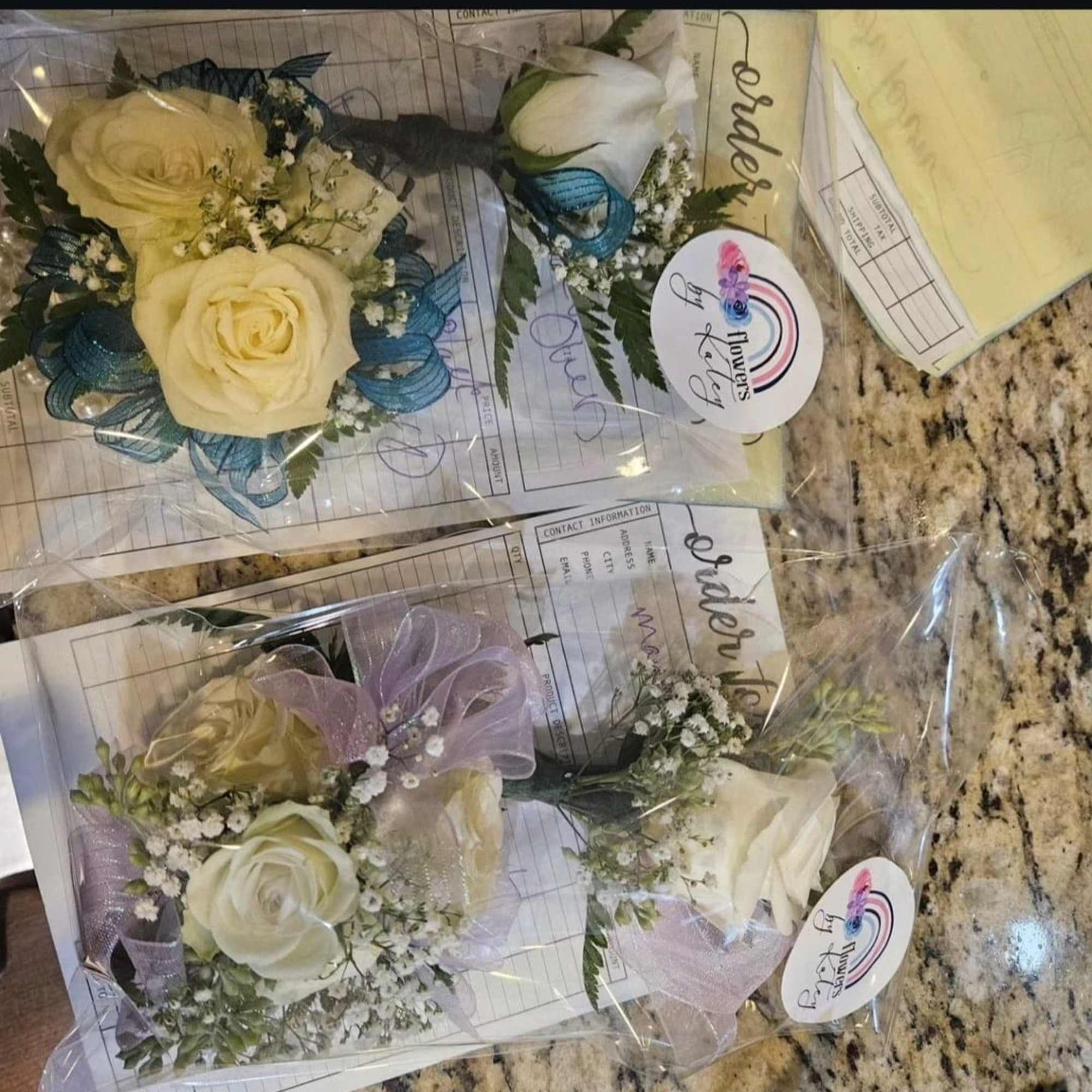 Small rose boutonnieres wrapped in clear plastic with ribbon accents