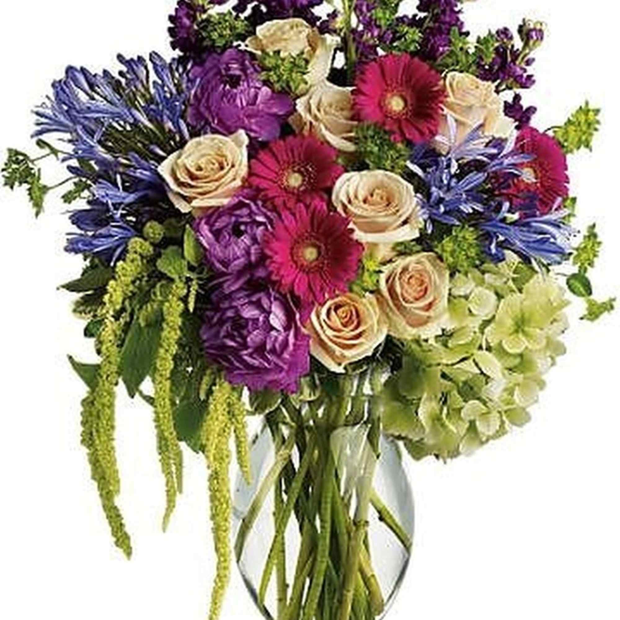 Tall mixed bouquet of purple, pink, cream, and green flowers in a clear glass vase
