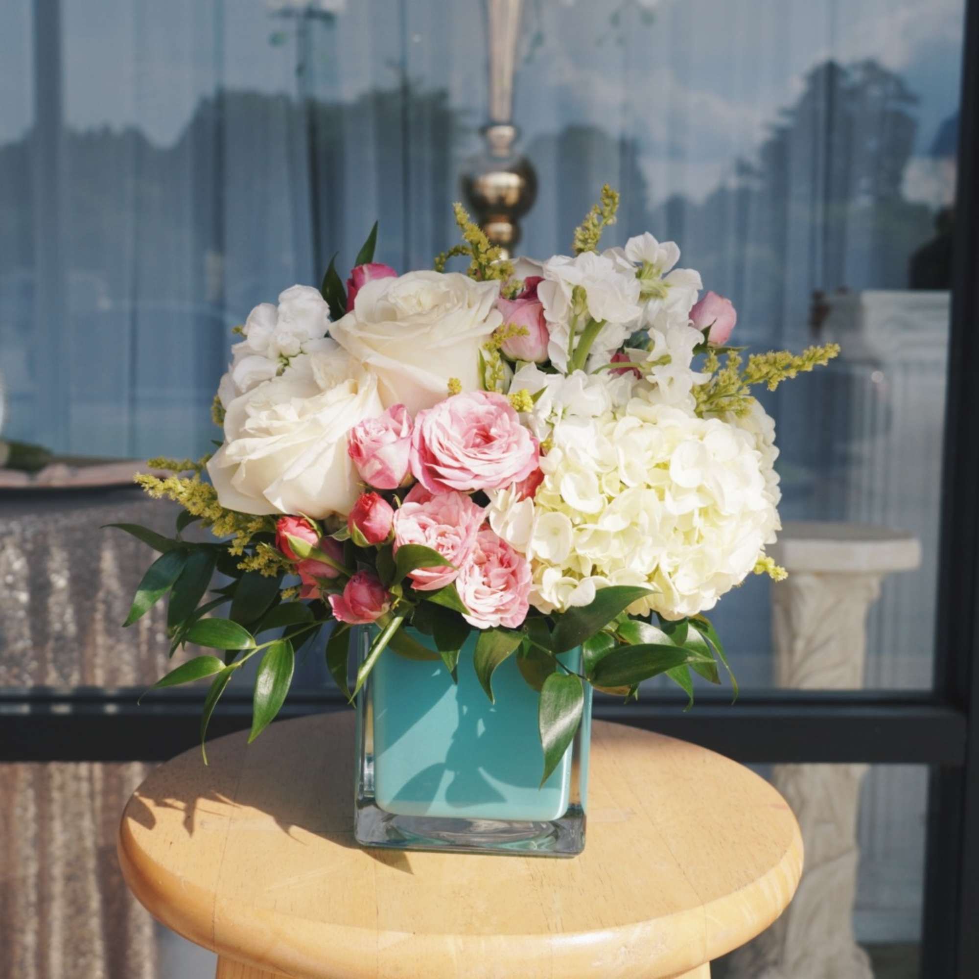 A soft cluster of blush-pink roses and creamy white hydrangea-like blooms framed