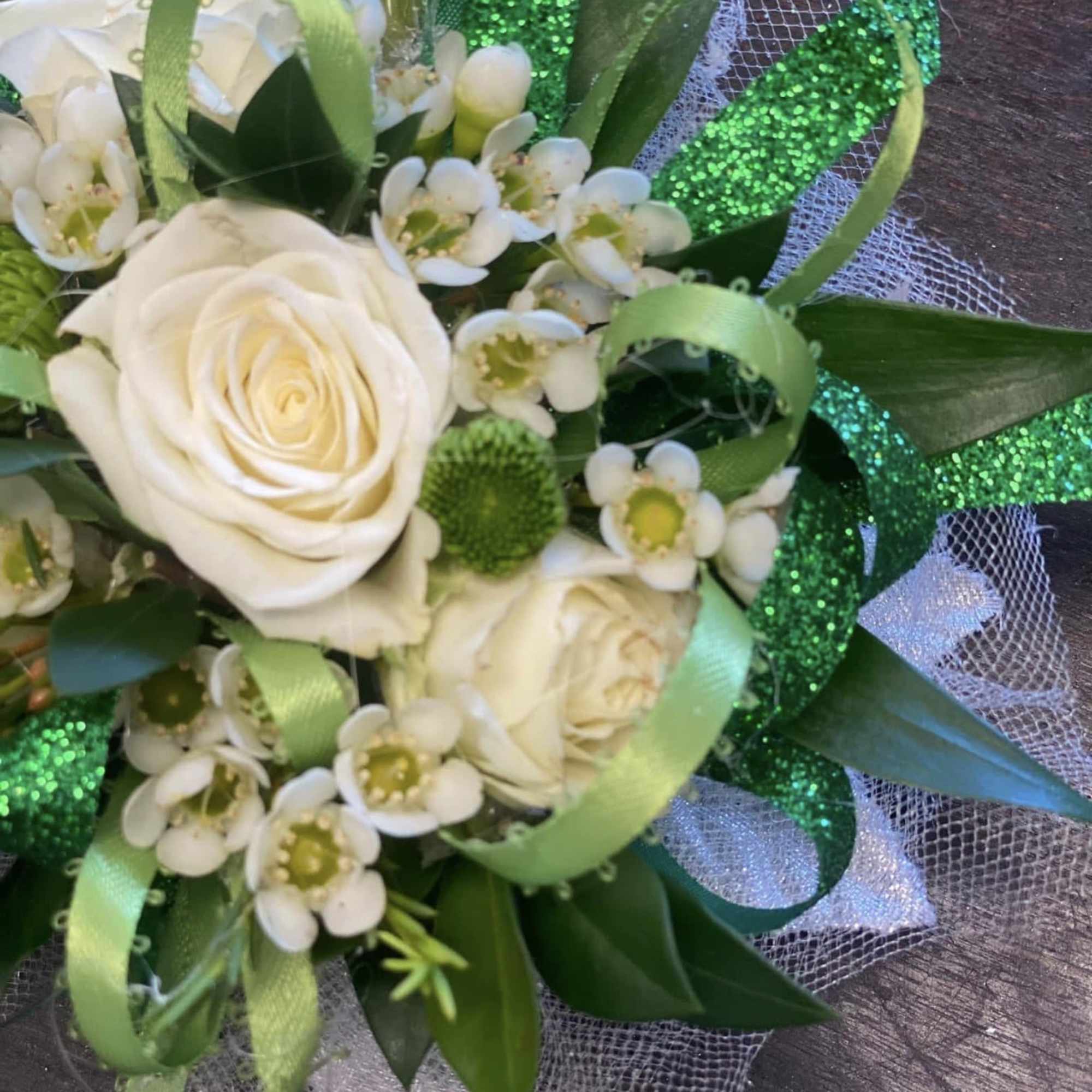 A timeless corsage featuring a pristine white rose nestled among fresh, lush