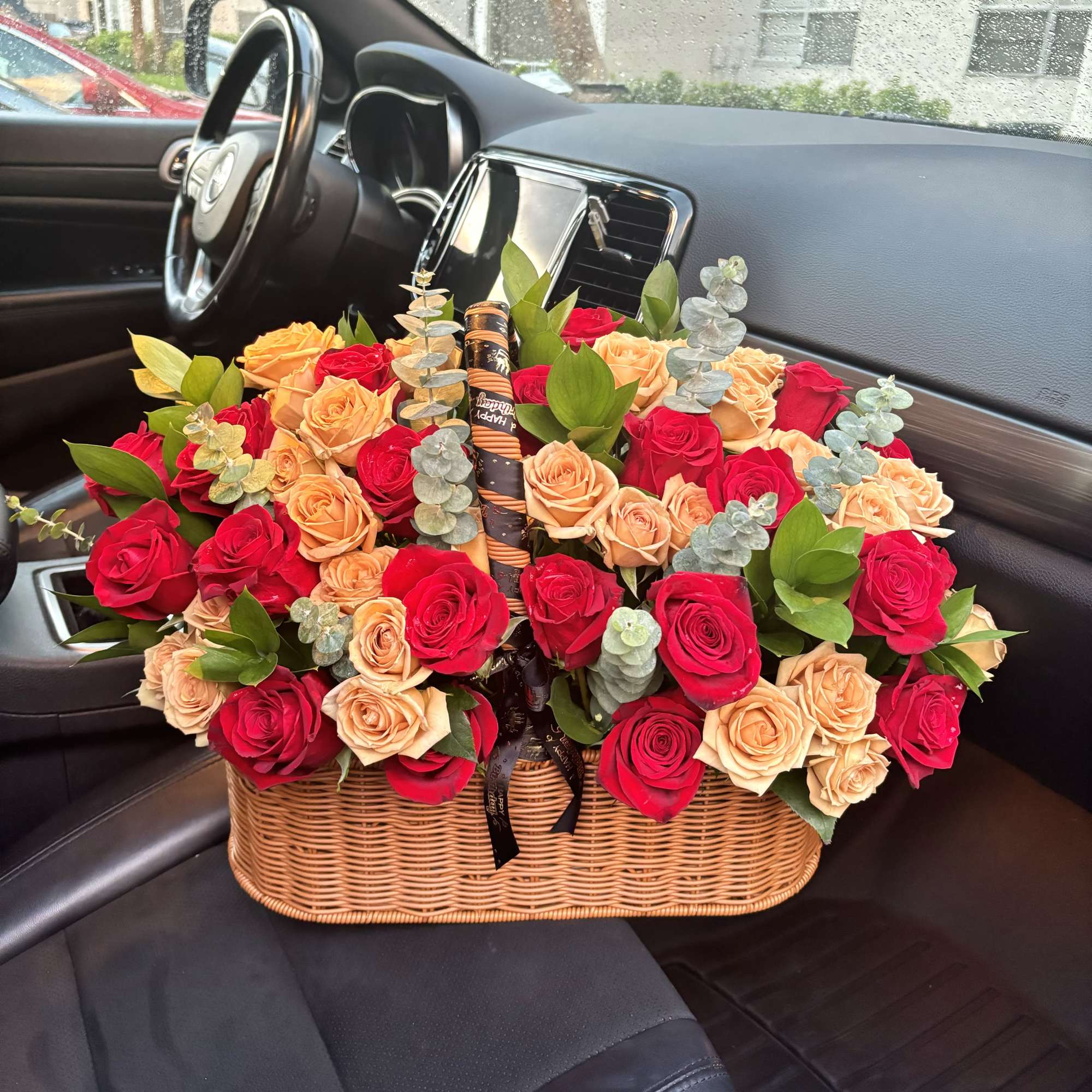Basket of red and peach roses with eucalyptus in a car seat