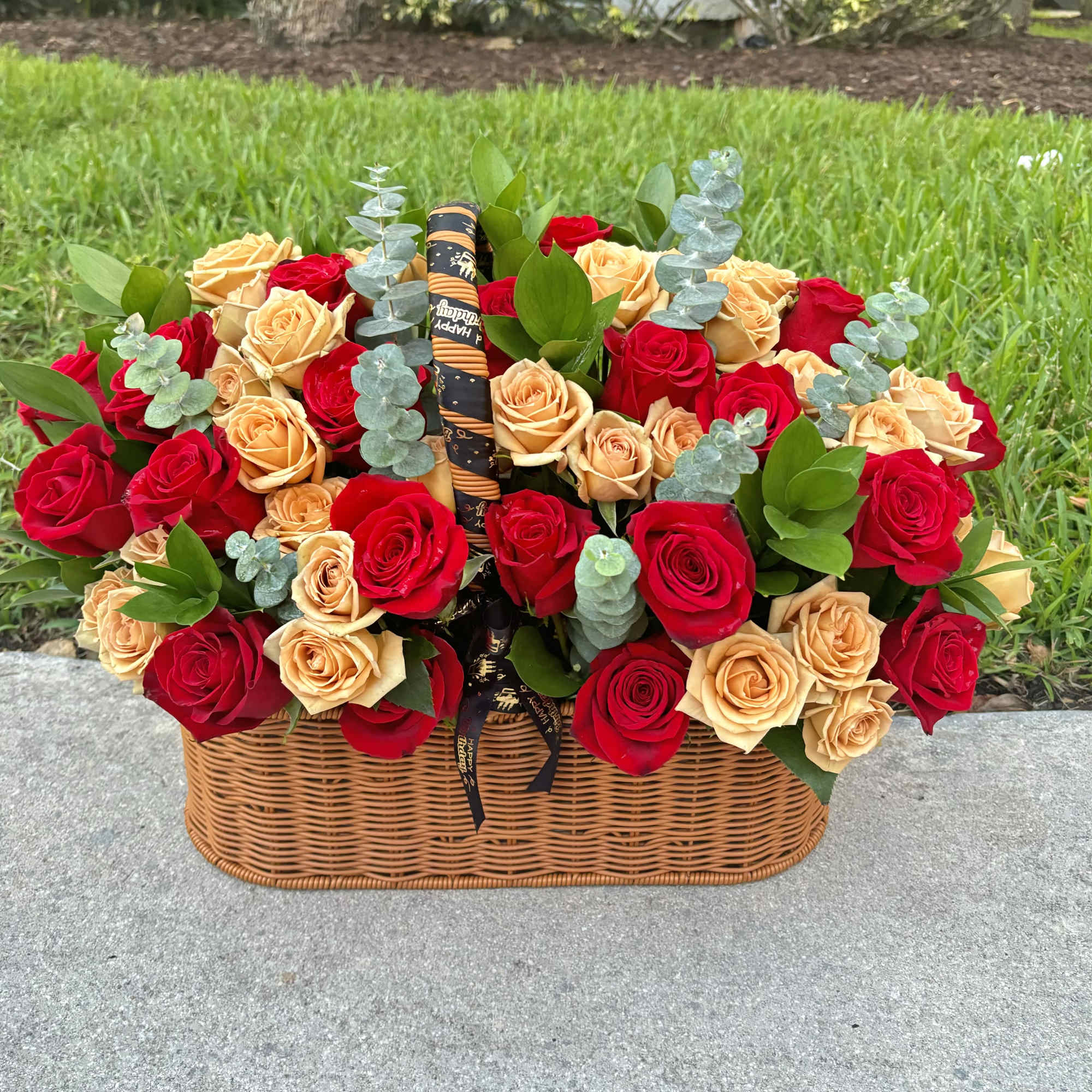 Basket of red and peach roses with eucalyptus and a ribbon