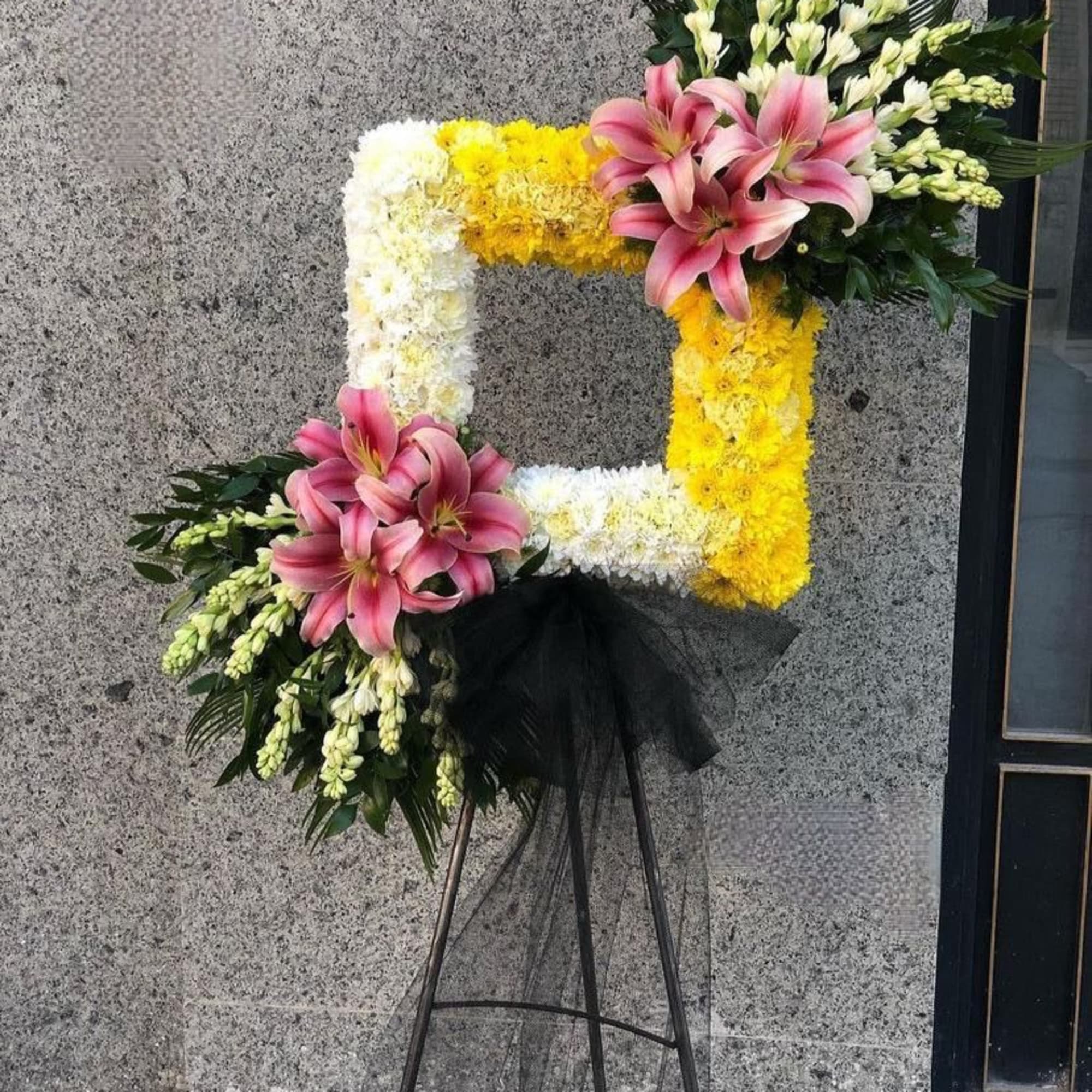 Floral standing wreath with pink lilies, white and yellow flowers on an easel