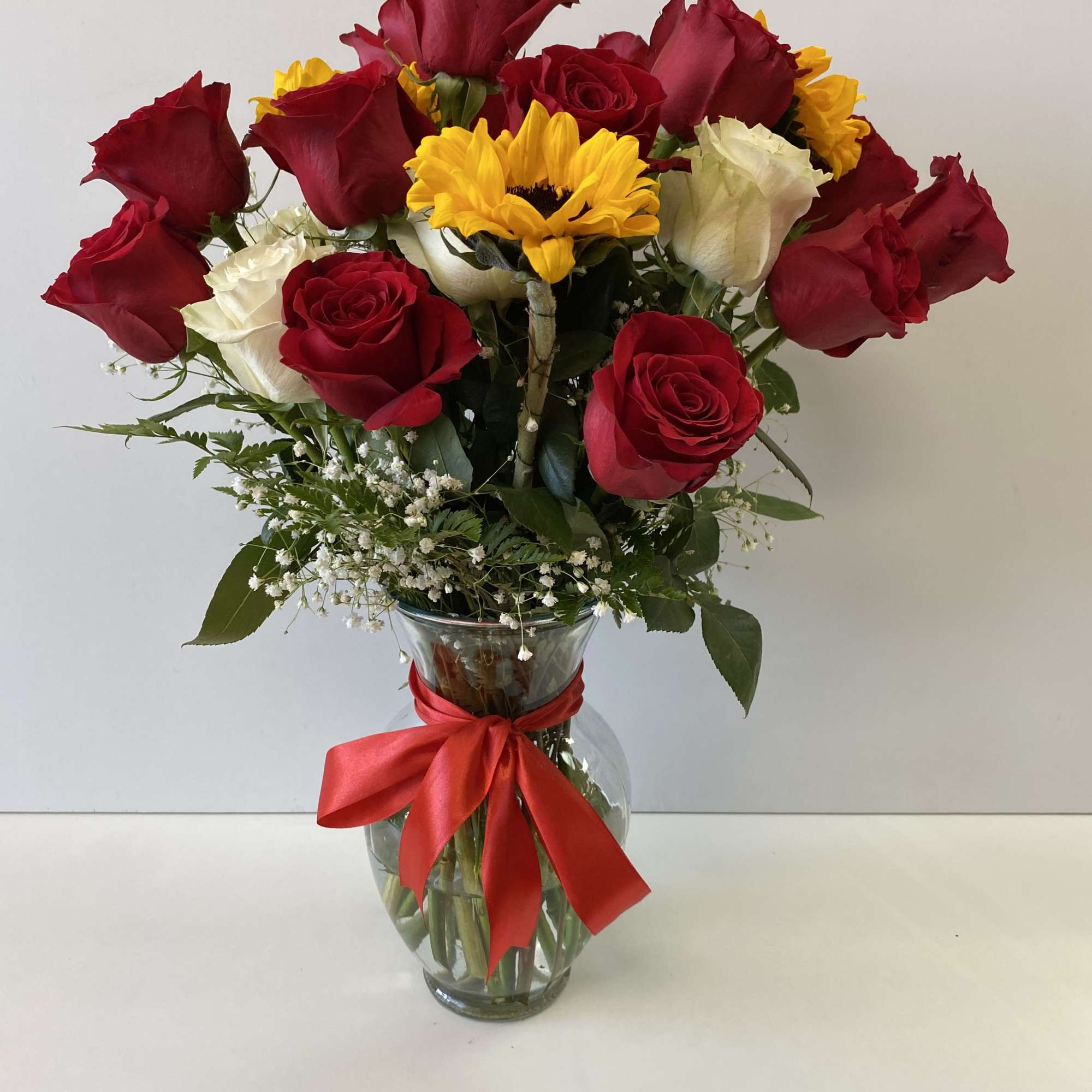 Bouquet of red and white roses with a yellow sunflower in a glass vase