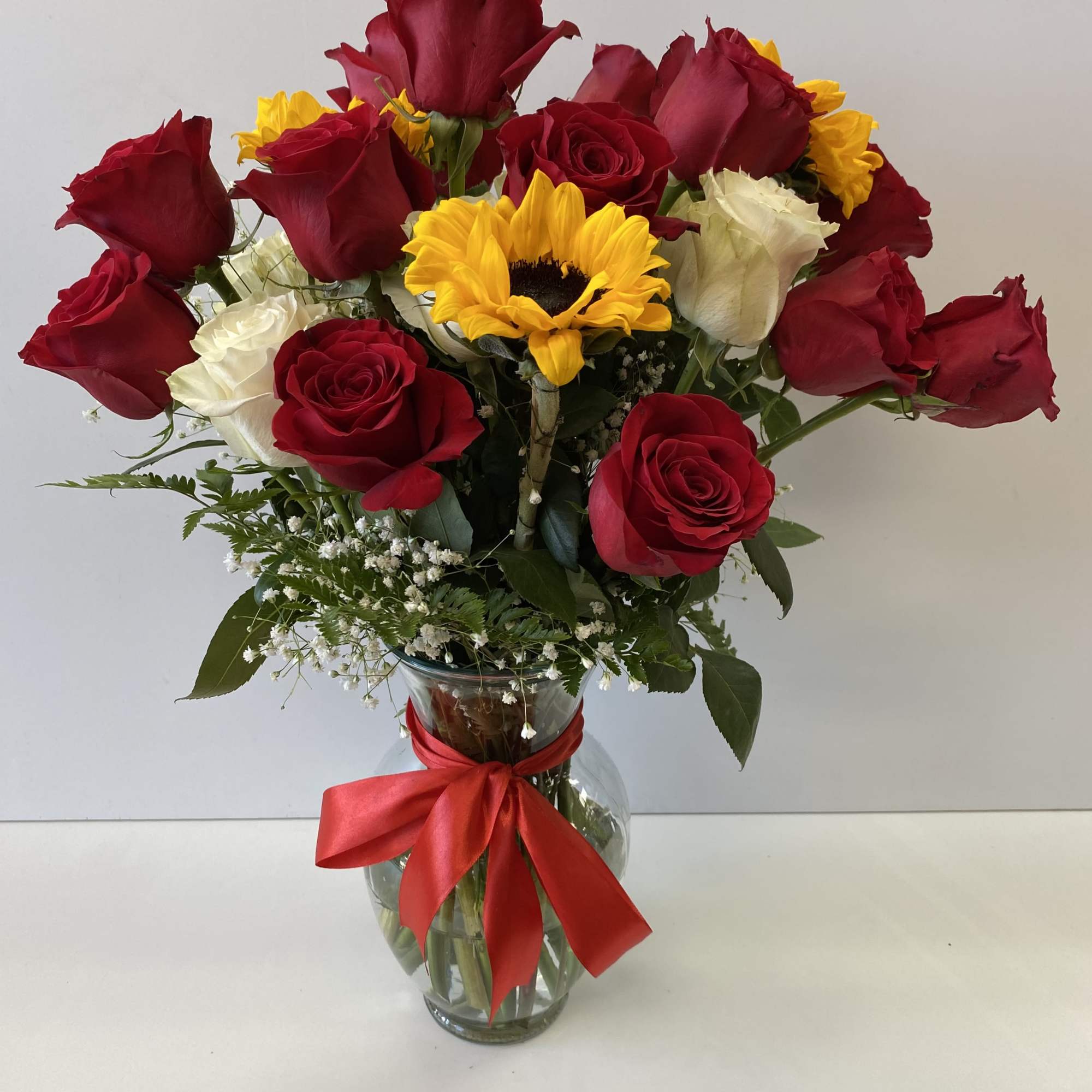 Bouquet of red and white roses with a yellow sunflower in a glass vase