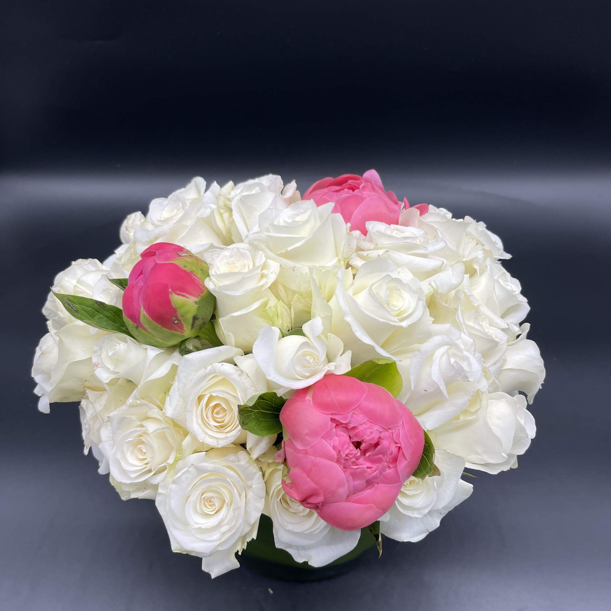 Three  stunning peonies surrounded by white roses. 
