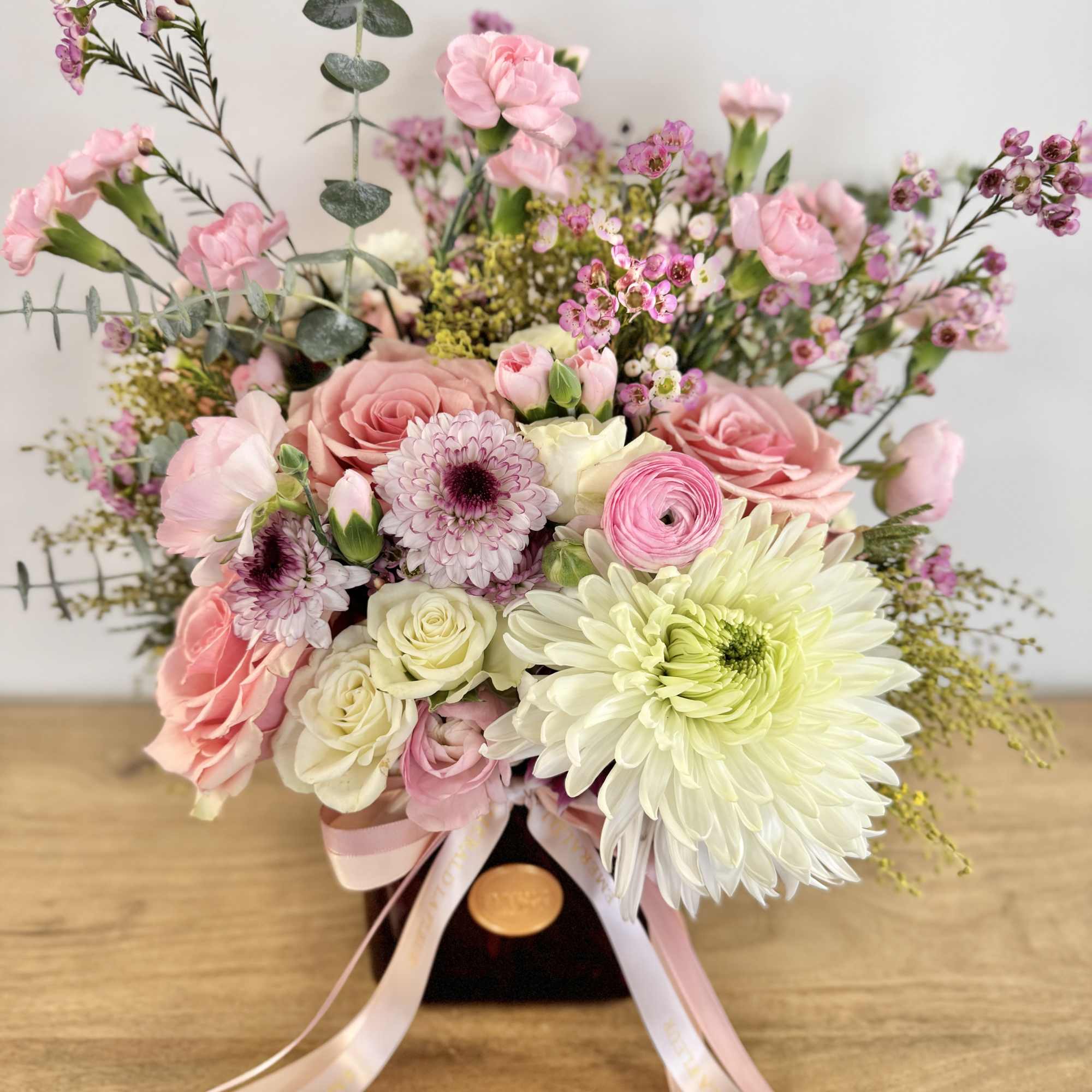 Pink and white bouquet with roses, chrysanthemums, and small filler flowers in a dark vase