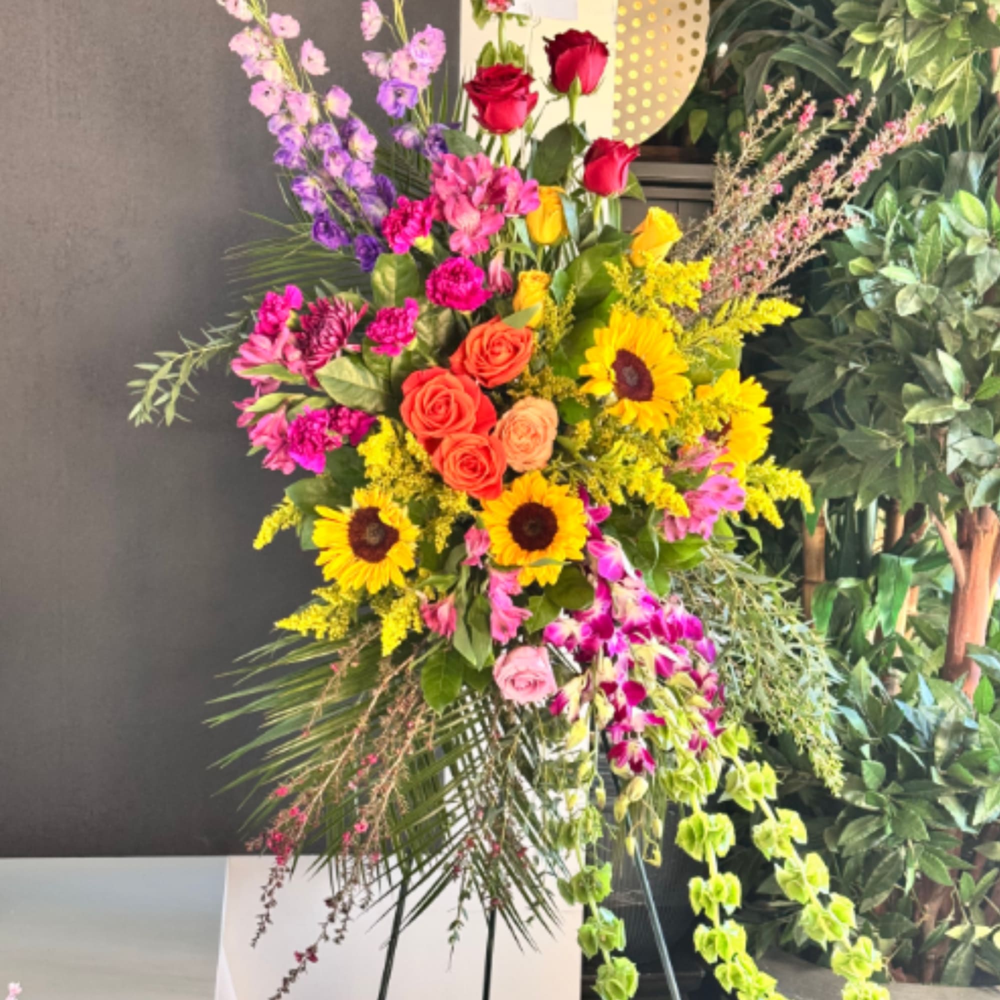 A vivid, tall standing sympathy spray that reads more like a celebratory