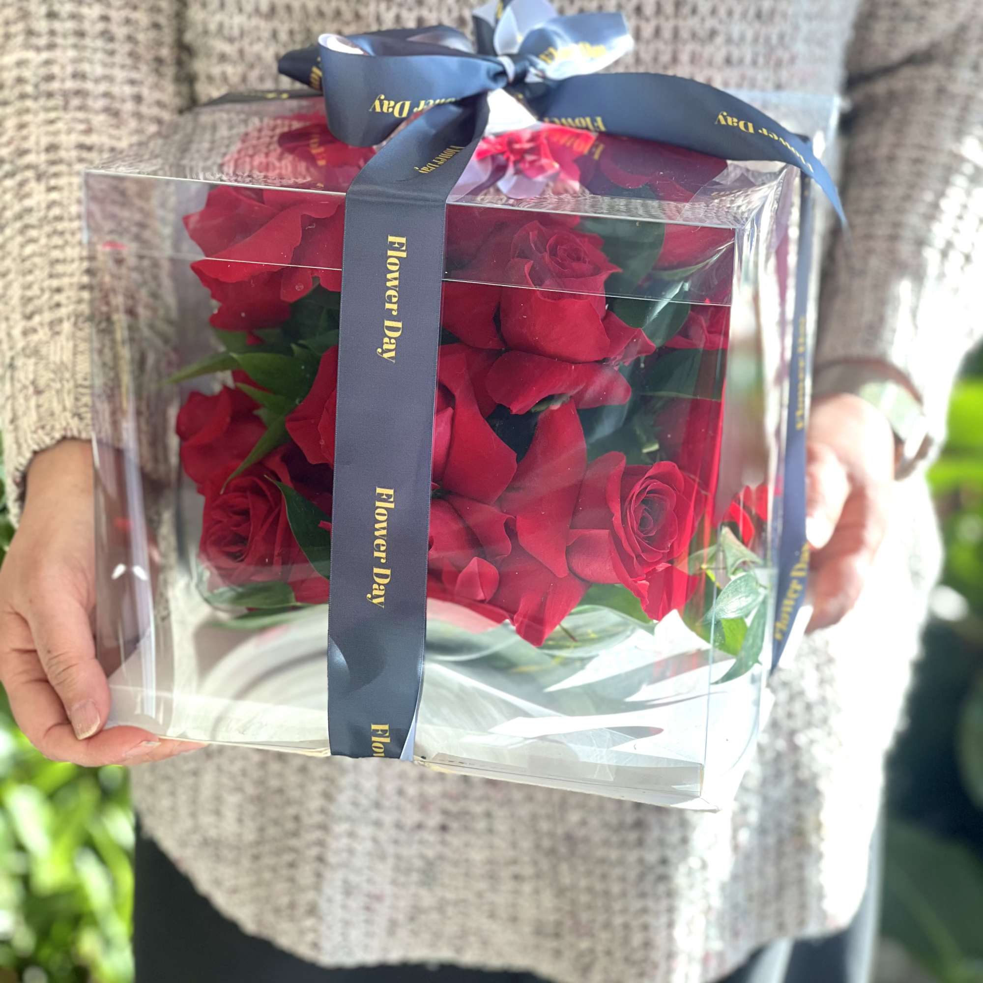Boxed bouquet of red roses tied with a blue ribbon