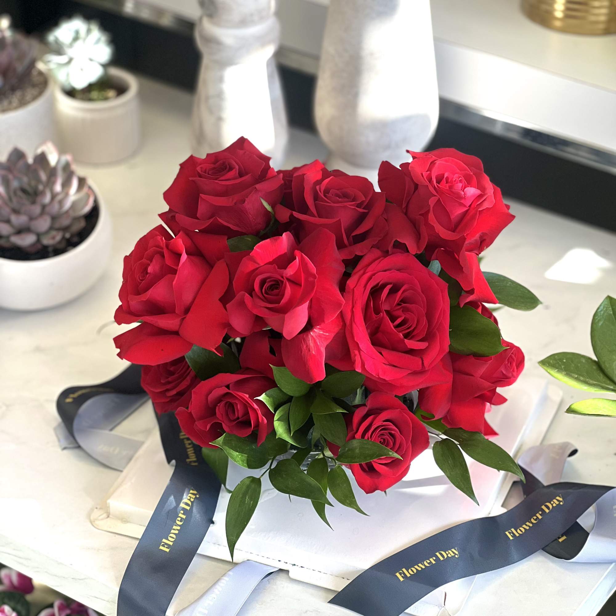 Bouquet of red roses with dark ribbon on a white box