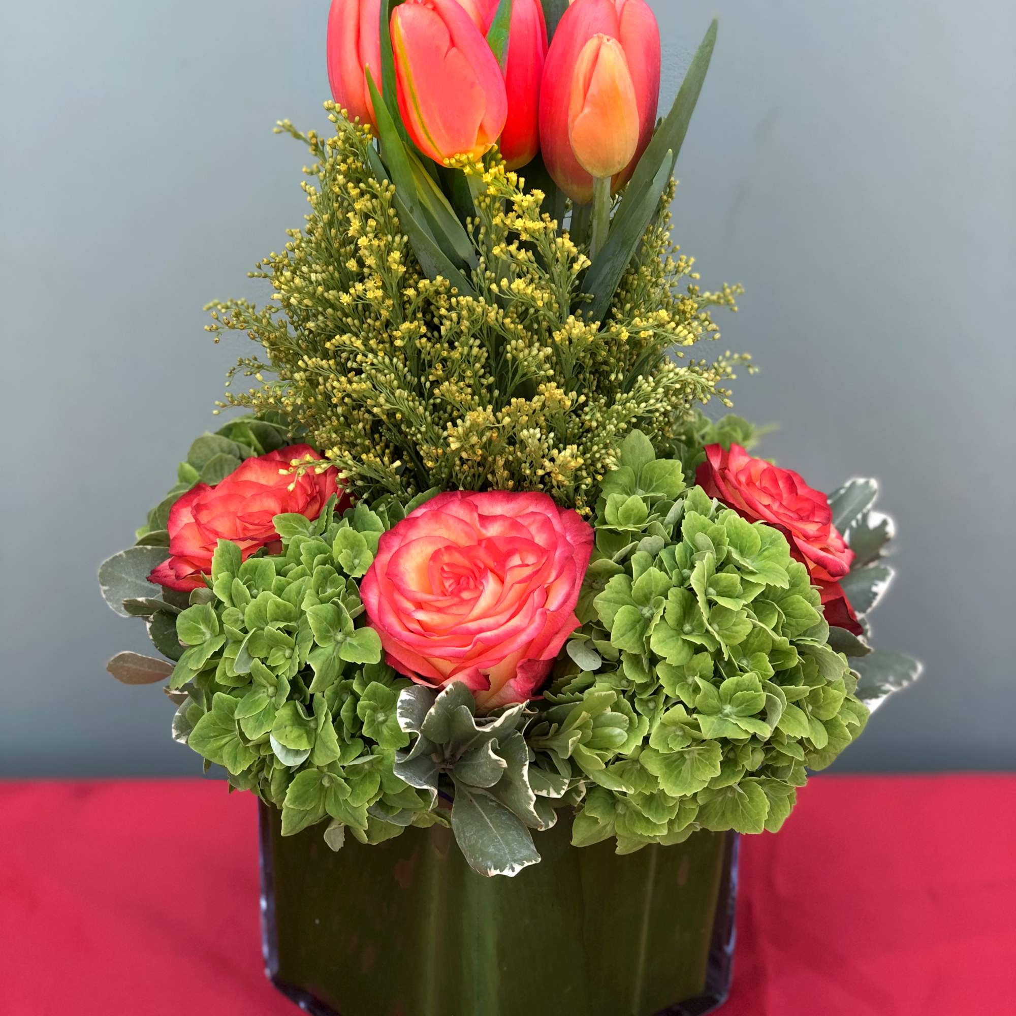 A low vase holding Roses, Hydrangeas and Tulips. 7" wide, 12" high.