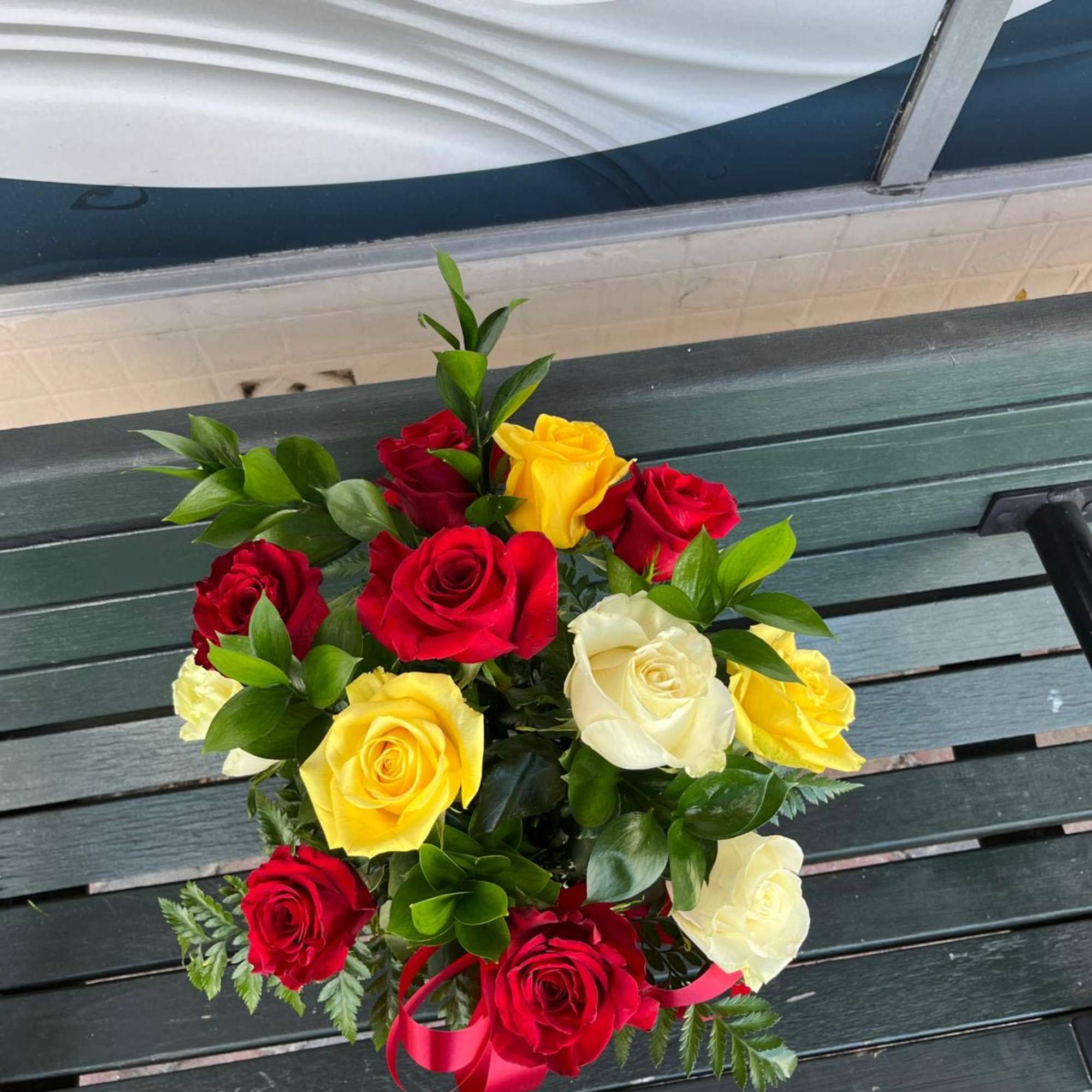 Bouquet of red, yellow, and white roses with a red ribbon