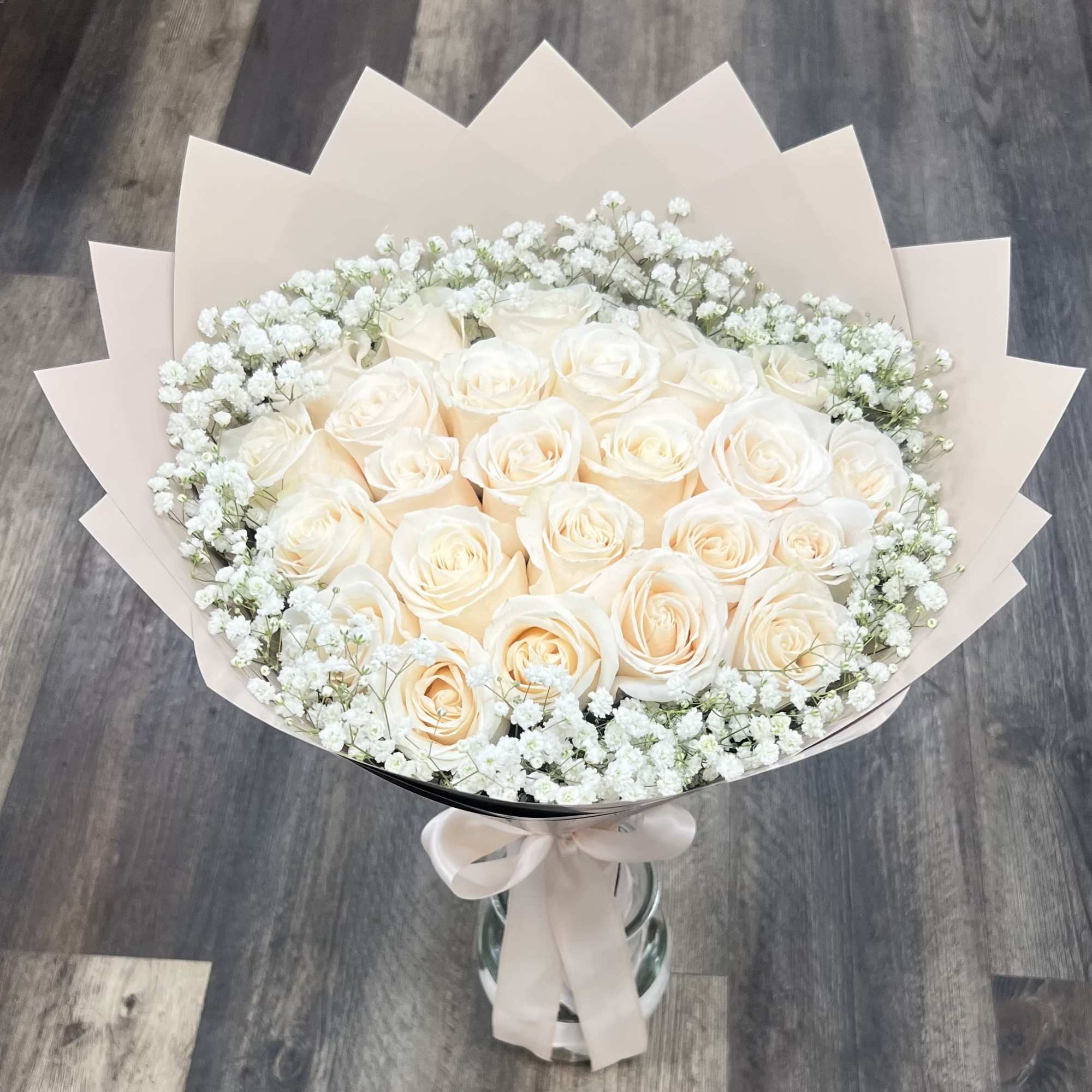 Bouquet of cream roses with white baby's breath in pale wrapping