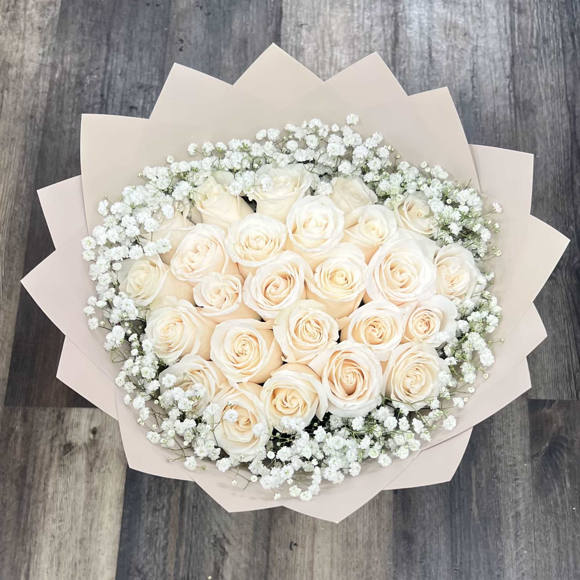 Bouquet of cream roses with white baby's breath in pale wrapping