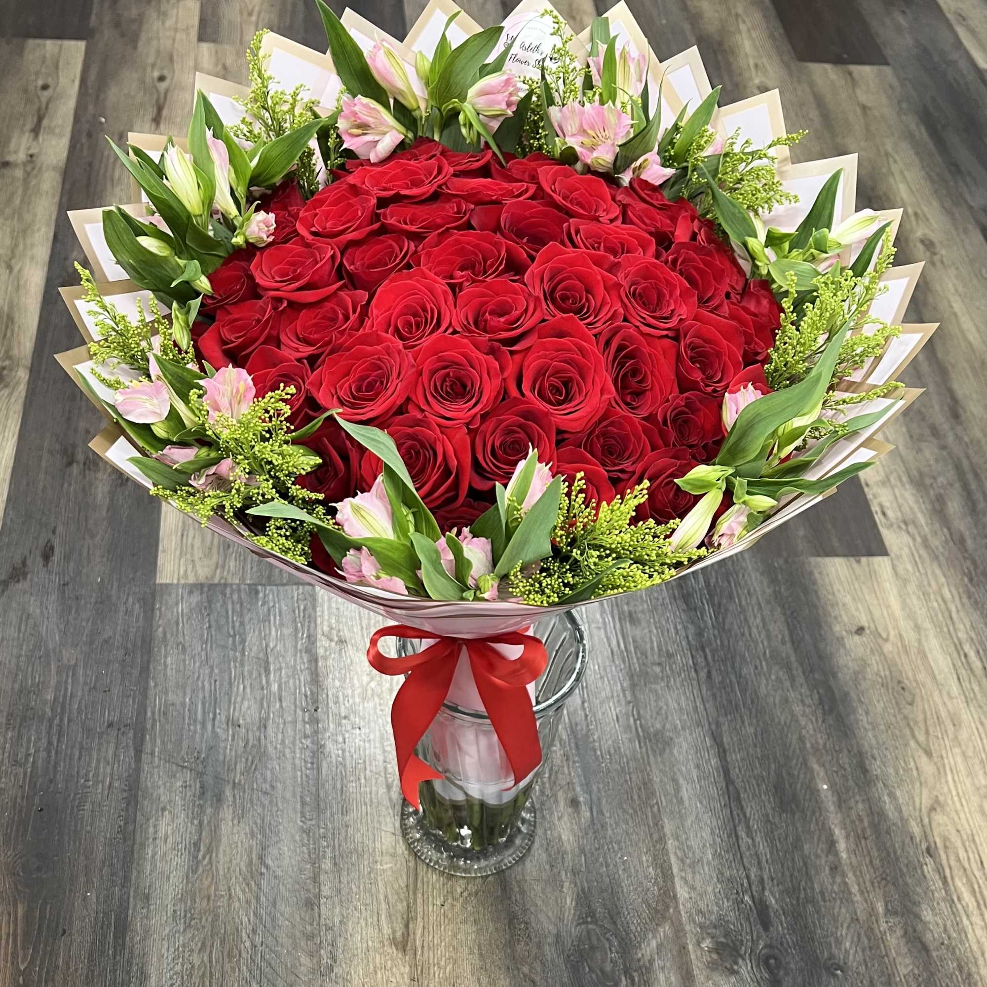 Bouquet of red roses with pink lilies in a glass vase