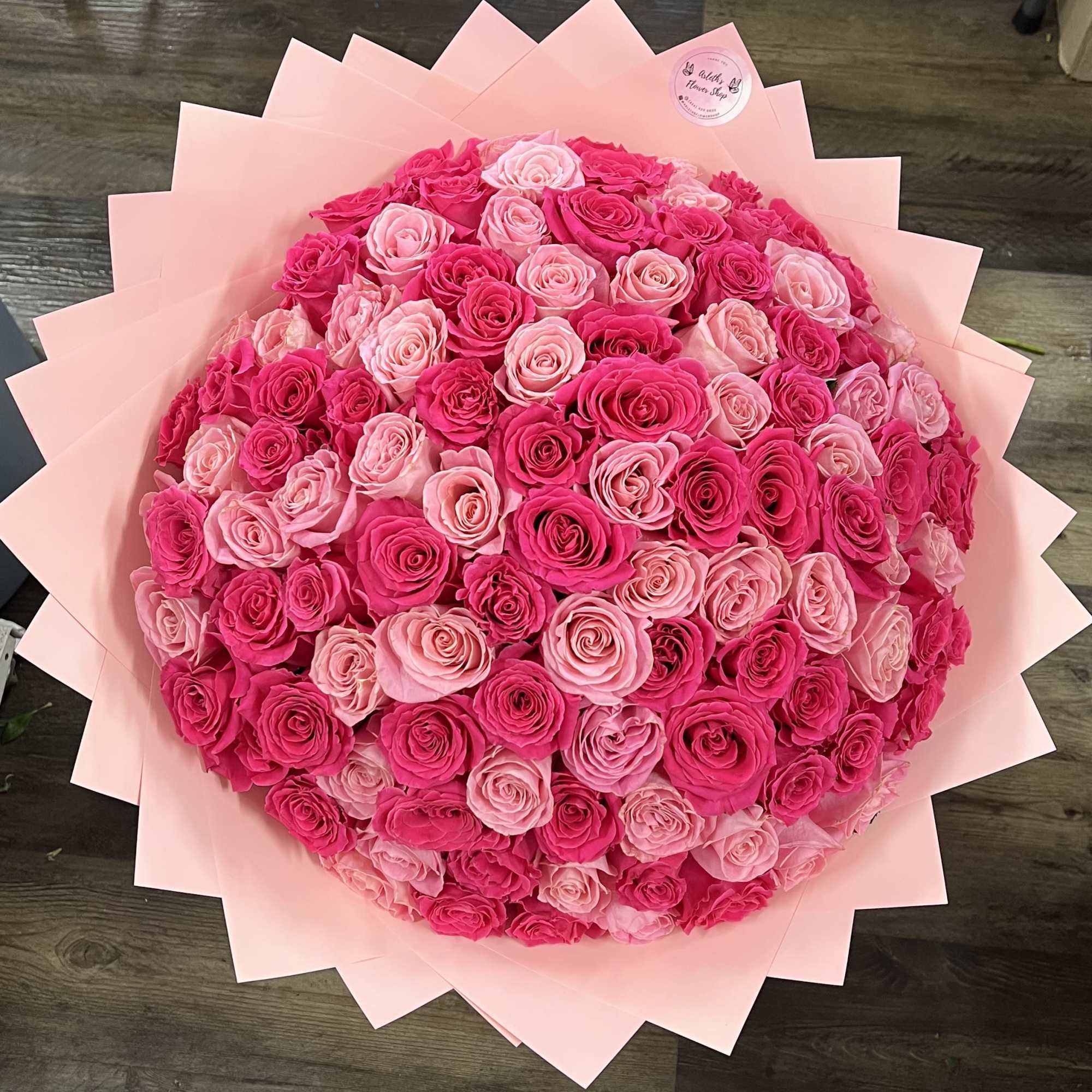 Large bouquet of pink and hot pink roses wrapped in pale pink paper
