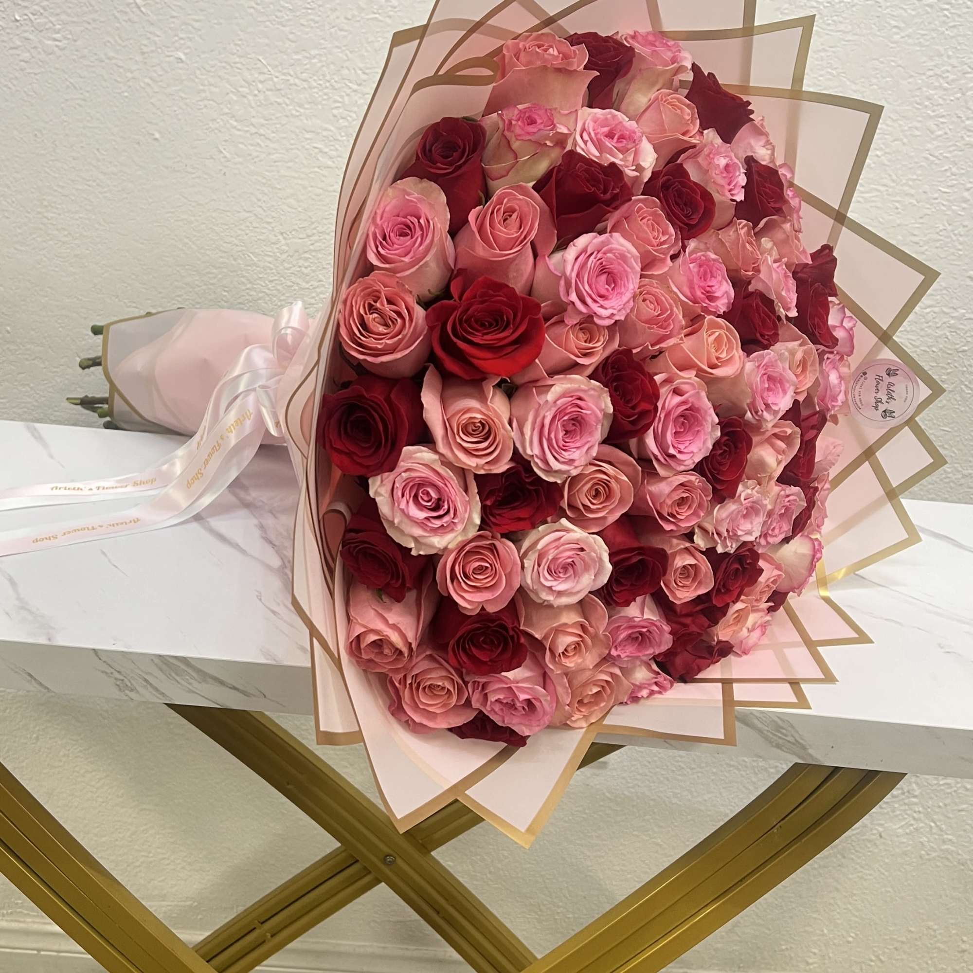 Large bouquet of pink and red roses wrapped in blush paper