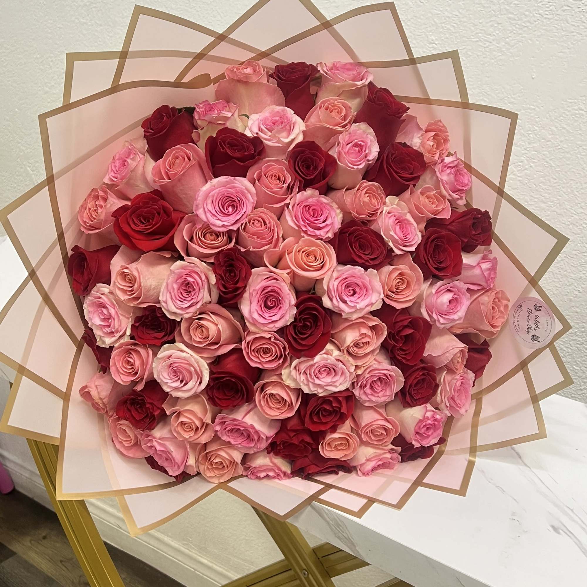 Large bouquet of pink and red roses wrapped in translucent paper