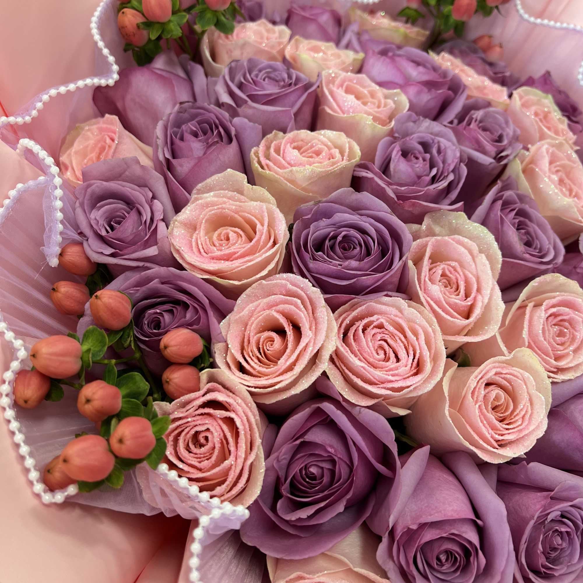 Bouquet of pink and lavender roses with berry accents in pink wrap
