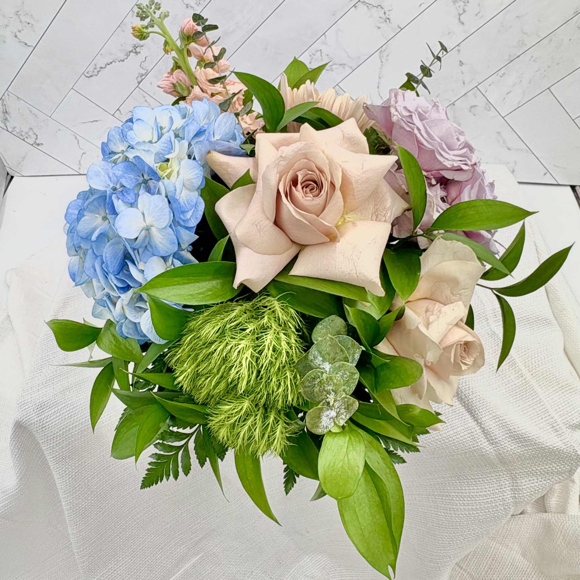 Quicksand roses, blue hydrangeas &amp; green dianthus in a summery low arrangement-vibrant