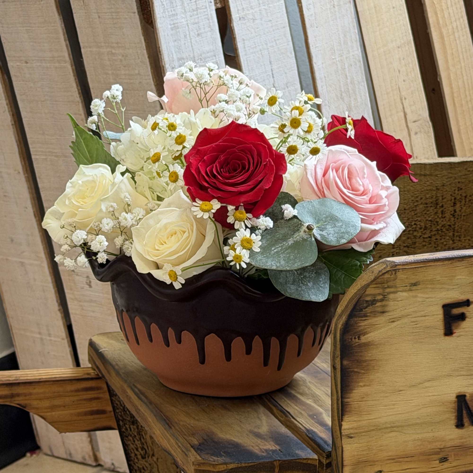A compact cluster of red, blush pink and creamy white roses makes