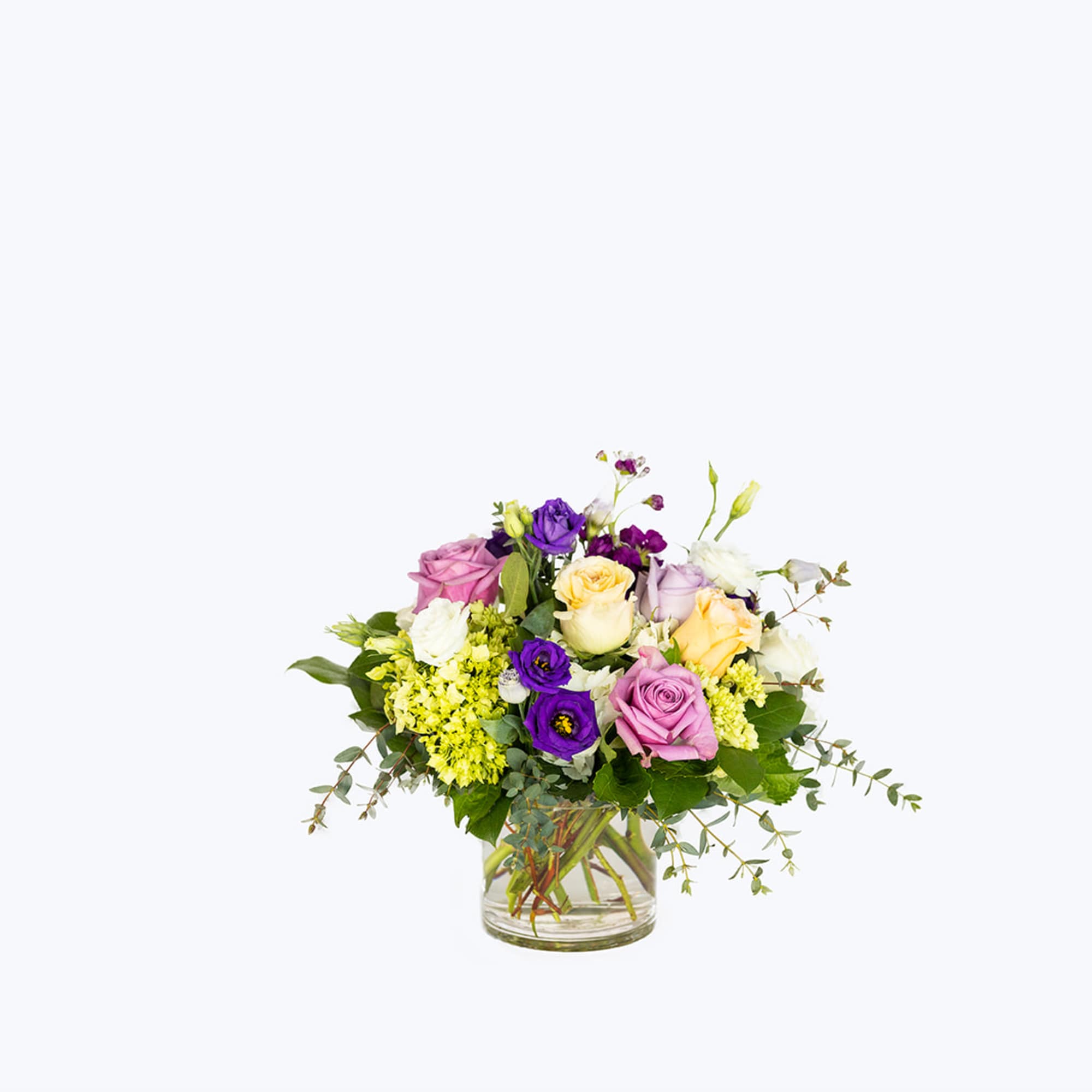 Mixed bouquet of roses and lisianthus in a clear glass vase