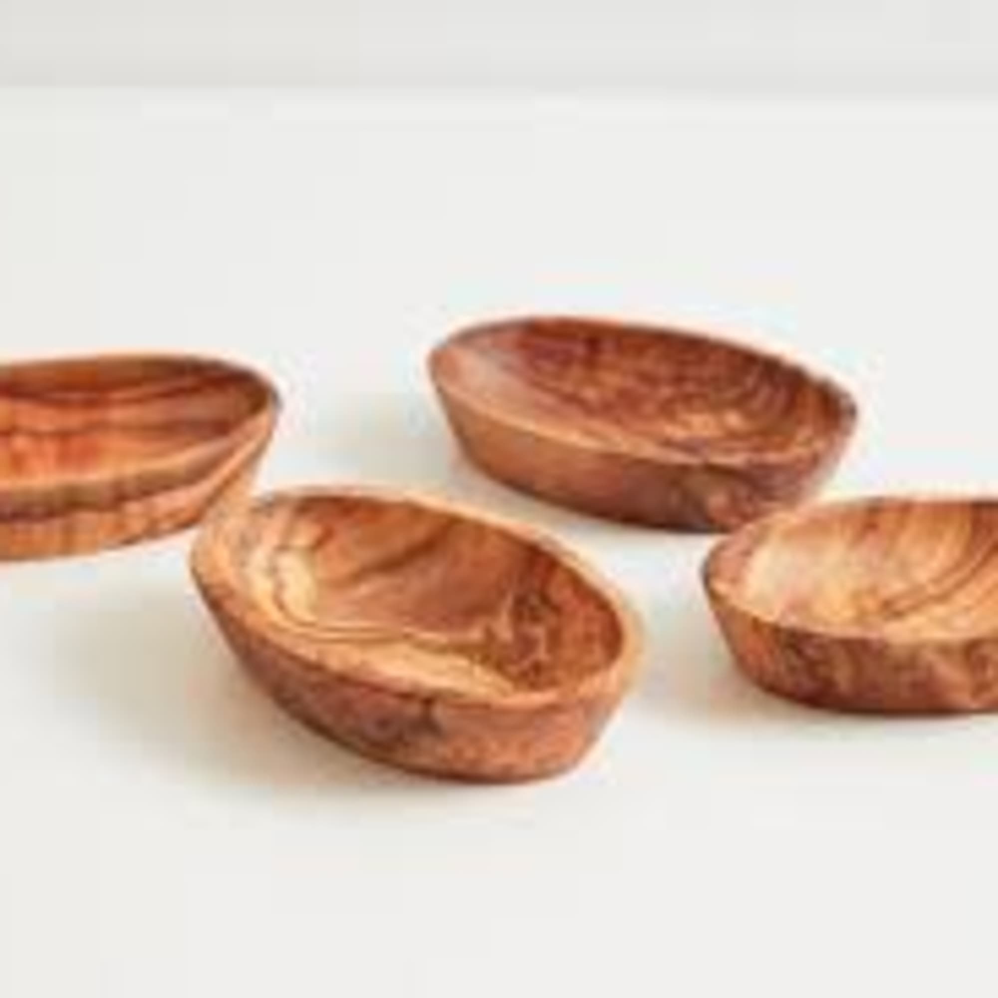 Four small wooden bowls on a white background