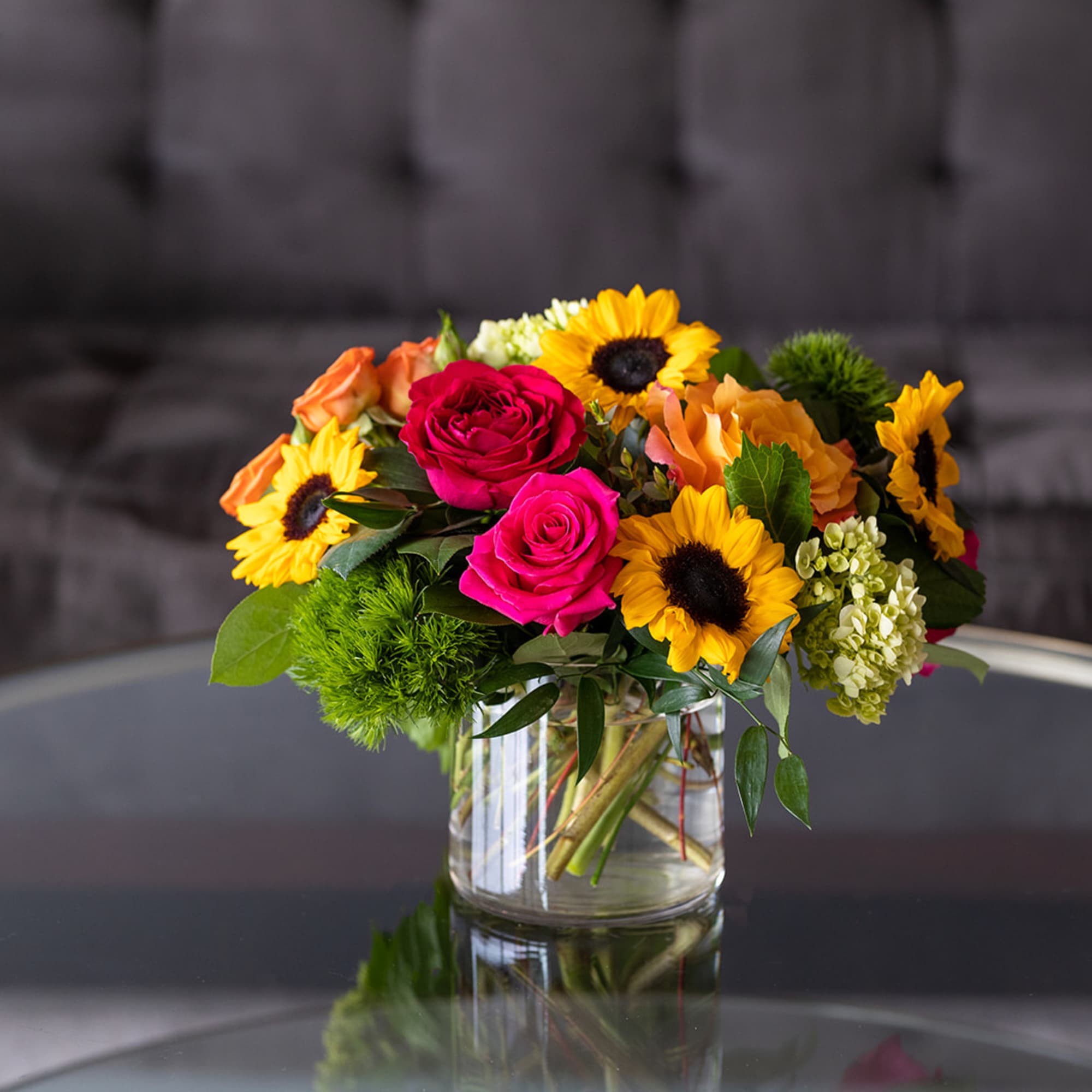 Bouquet of sunflowers and pink roses in a clear glass vase