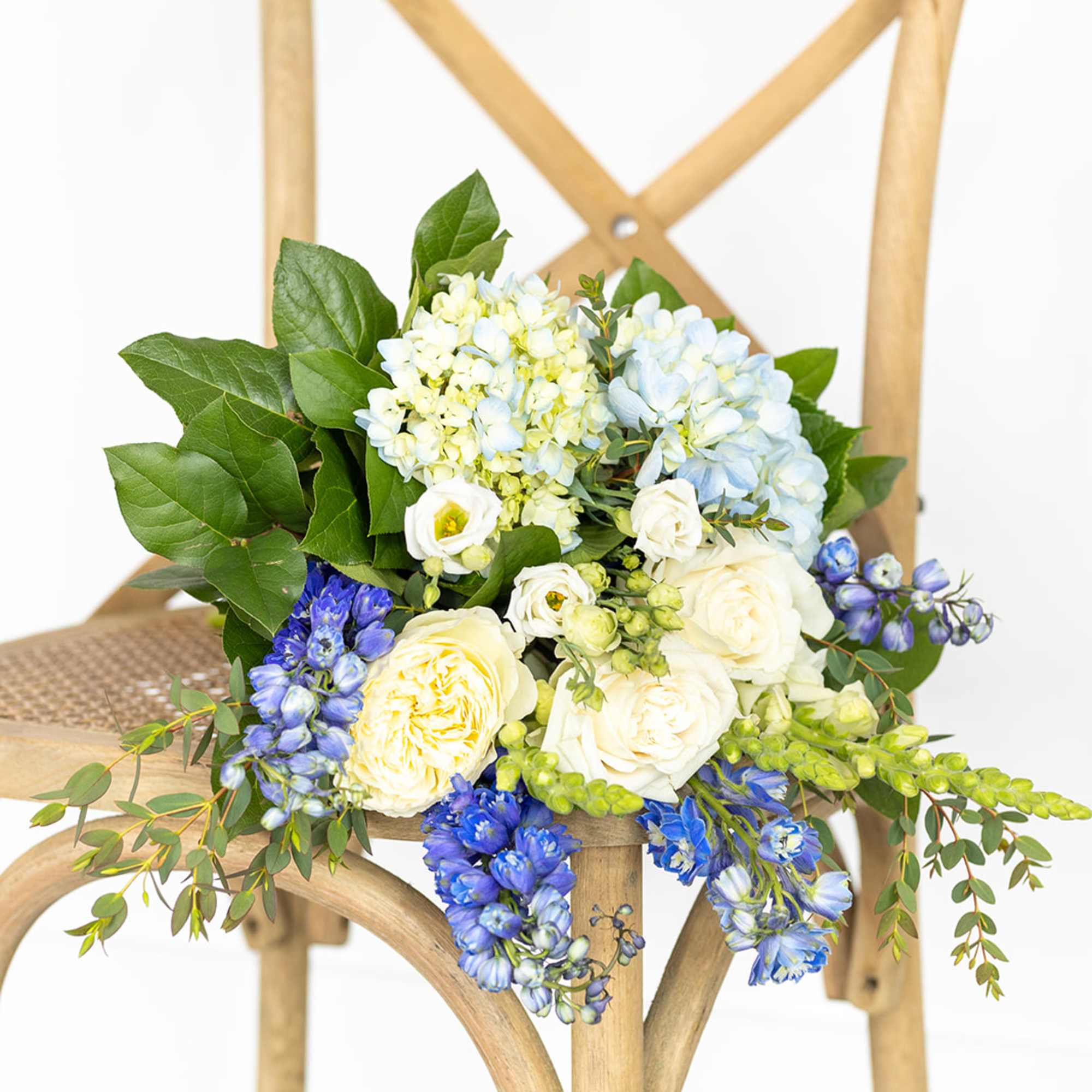 Blue and white floral bouquet draped over a wooden chair