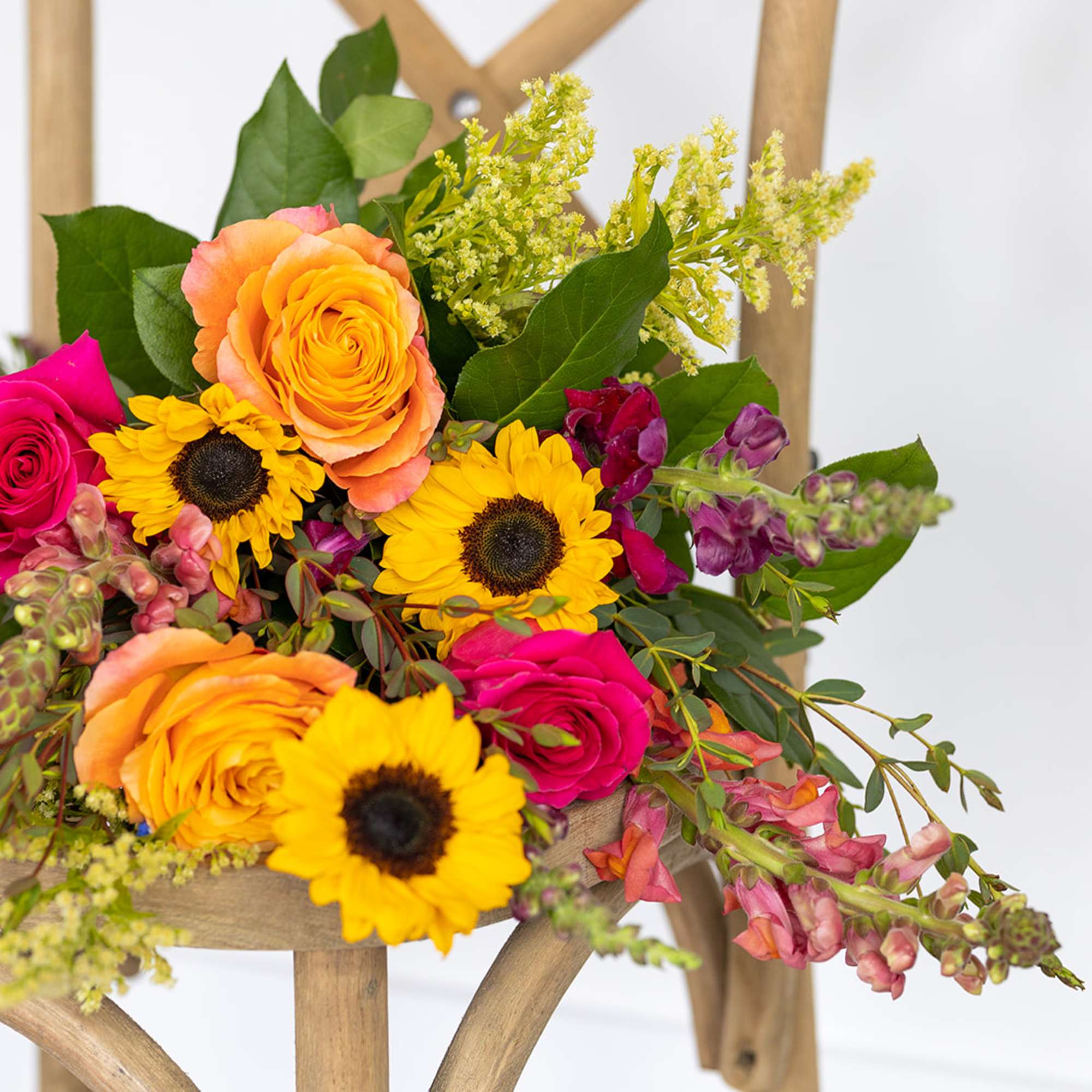 Bright bouquet of roses and sunflowers with mixed greenery
