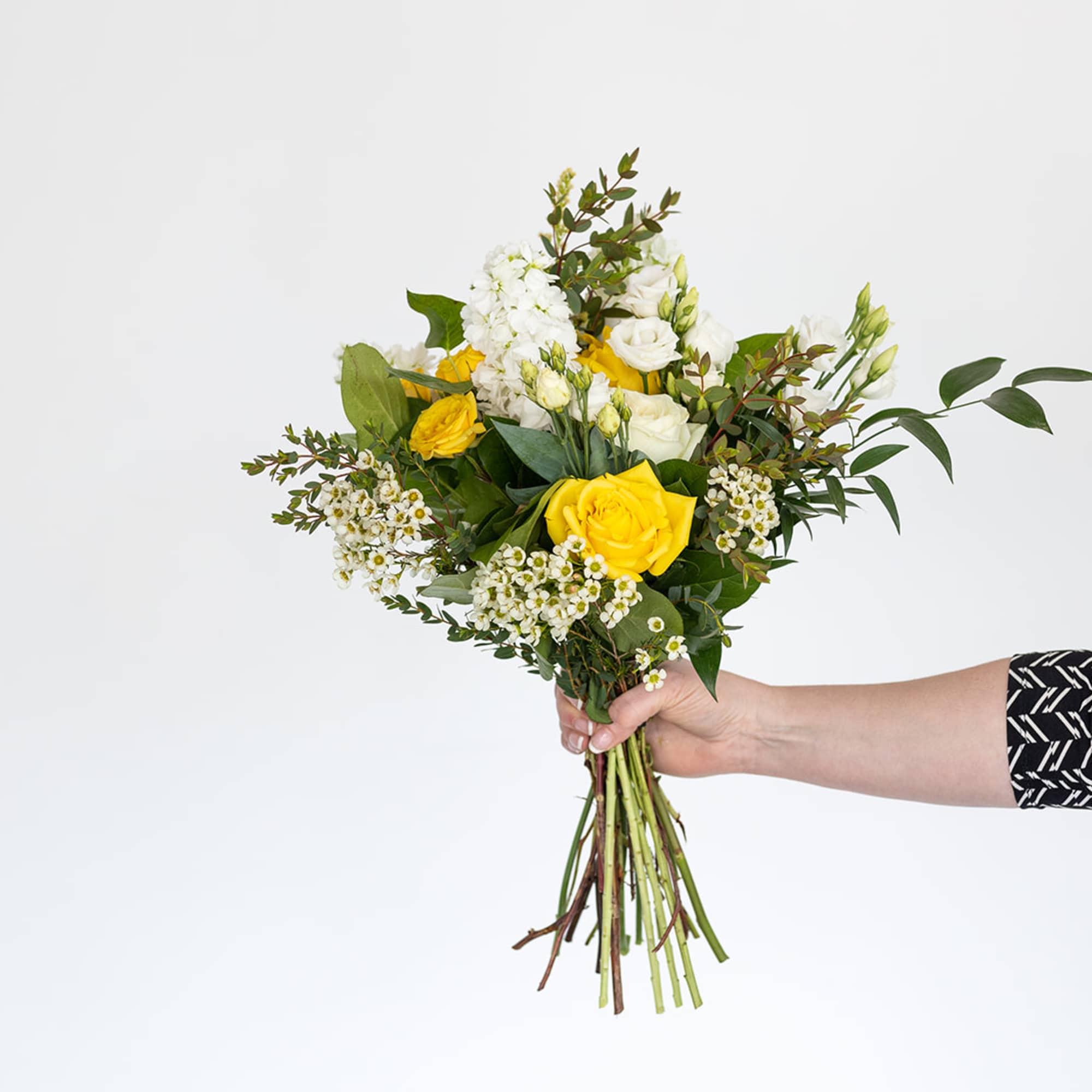 Handheld bouquet of yellow and white flowers with greenery