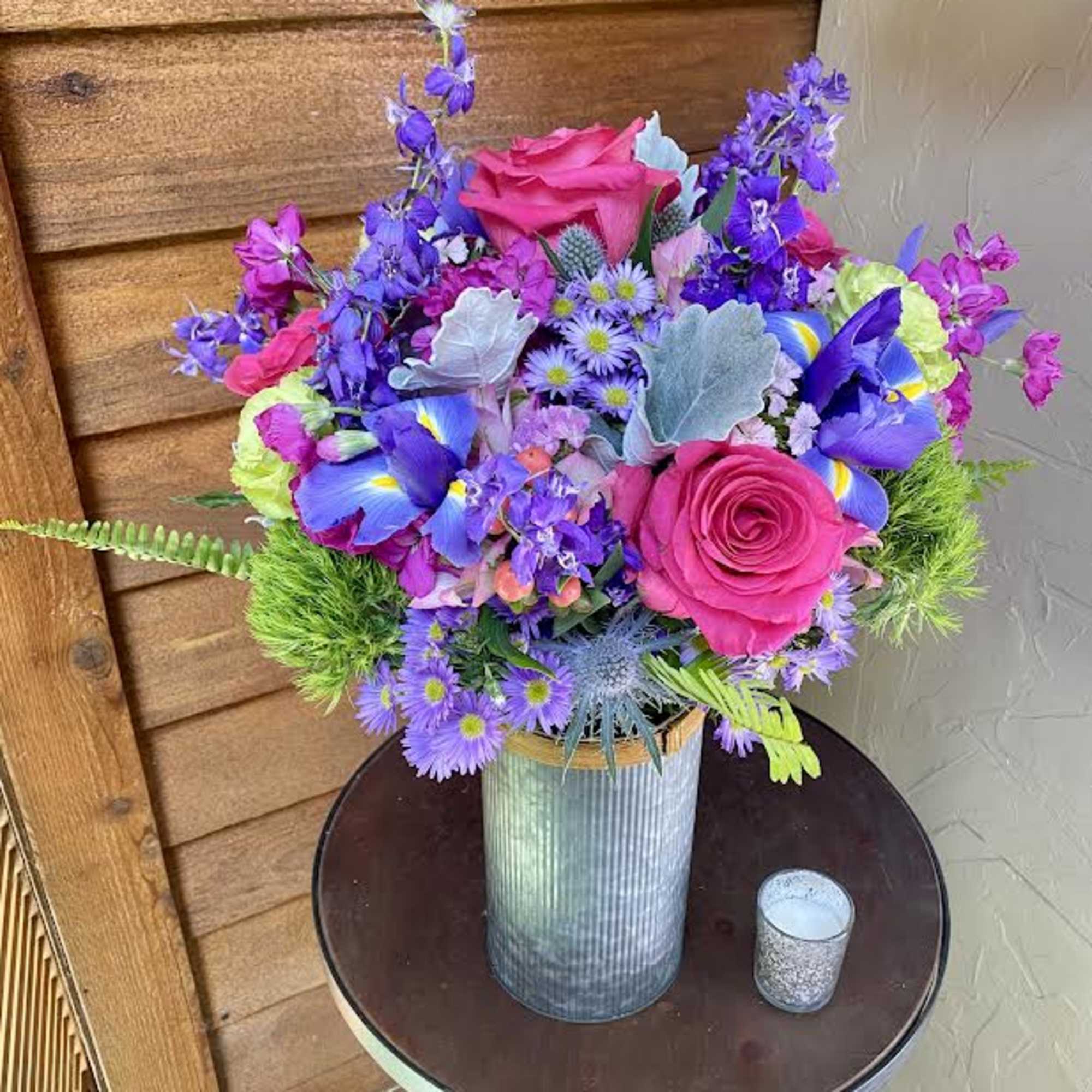 Bright mixed bouquet in a ribbed metal vase with pink roses and purple flowers