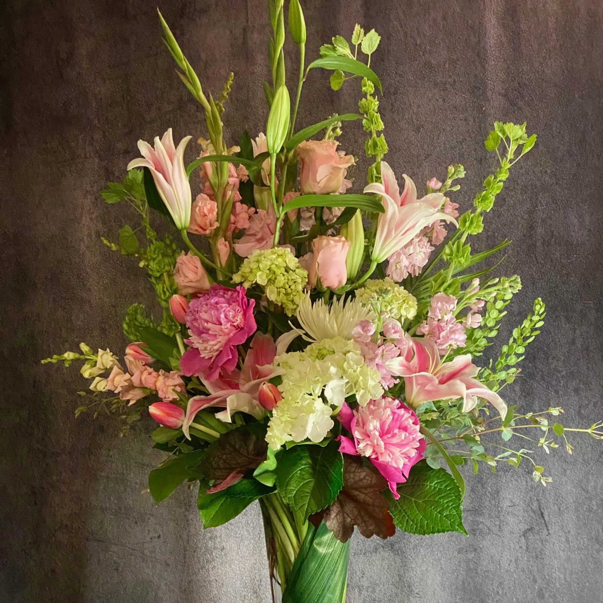 Tall pink and white floral arrangement in a glass vase