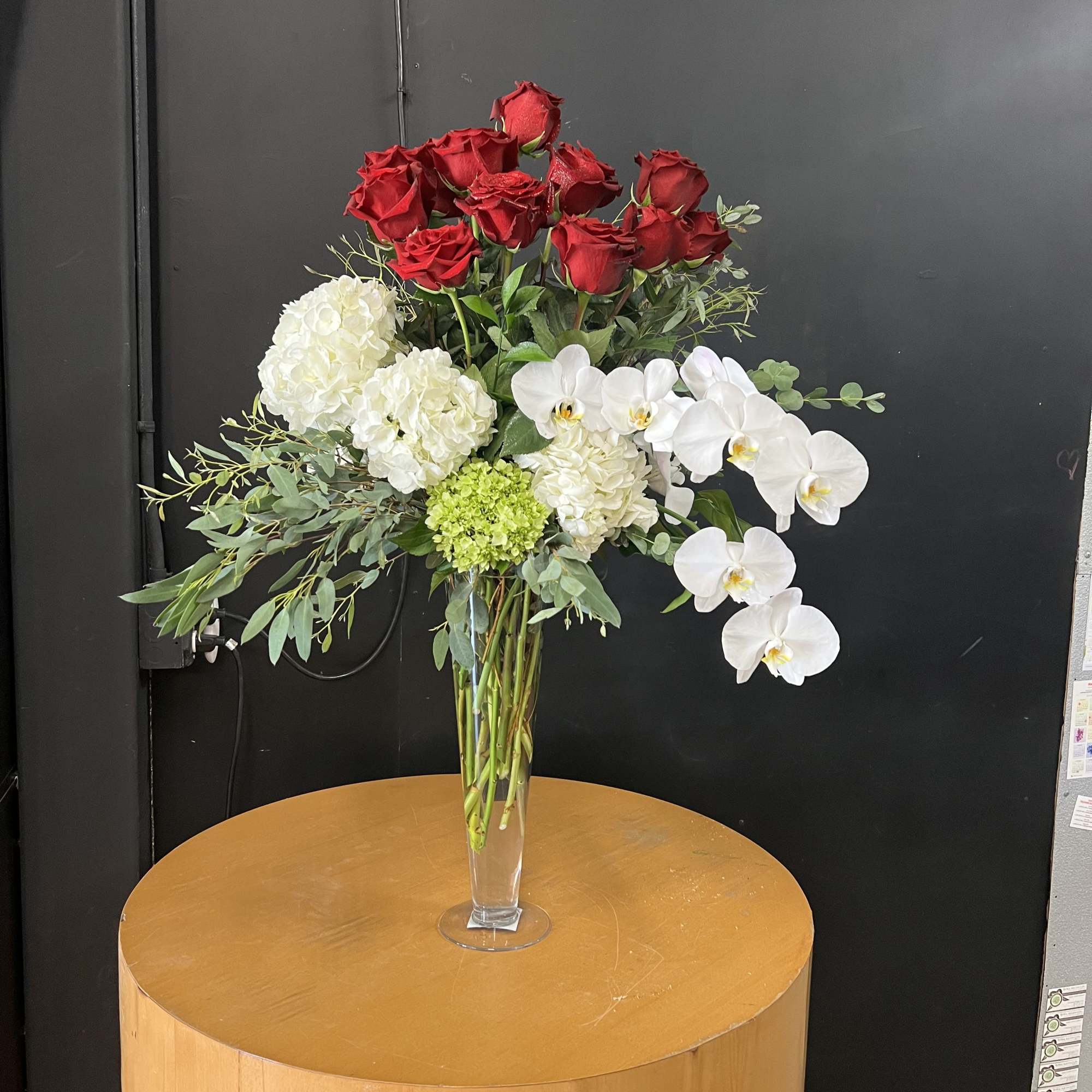 A striking tall bouquet that pairs classic roses with cascading phalaenopsis orchids