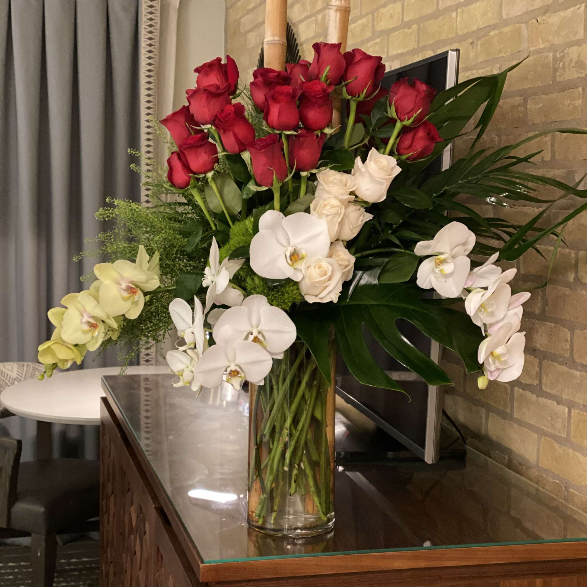 A striking tall bouquet that pairs classic roses with cascading phalaenopsis orchids