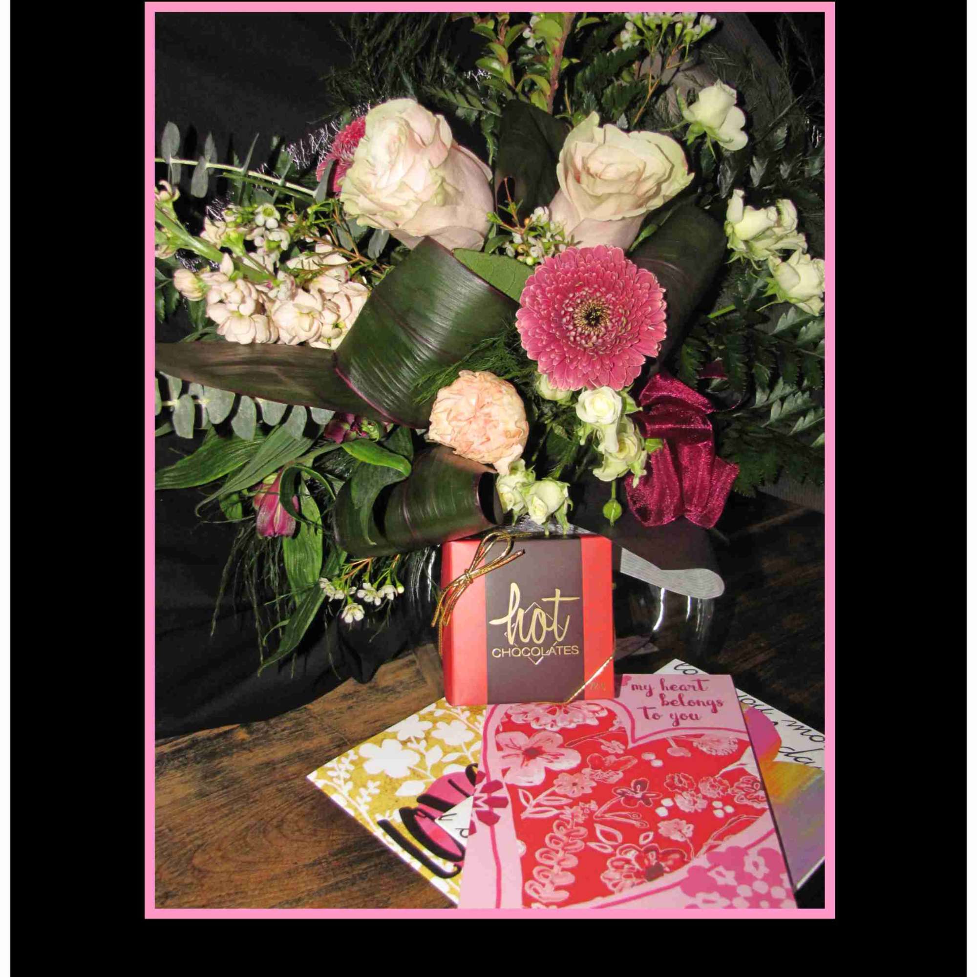 Bouquet of pale roses and pink gerbera with chocolates and cards