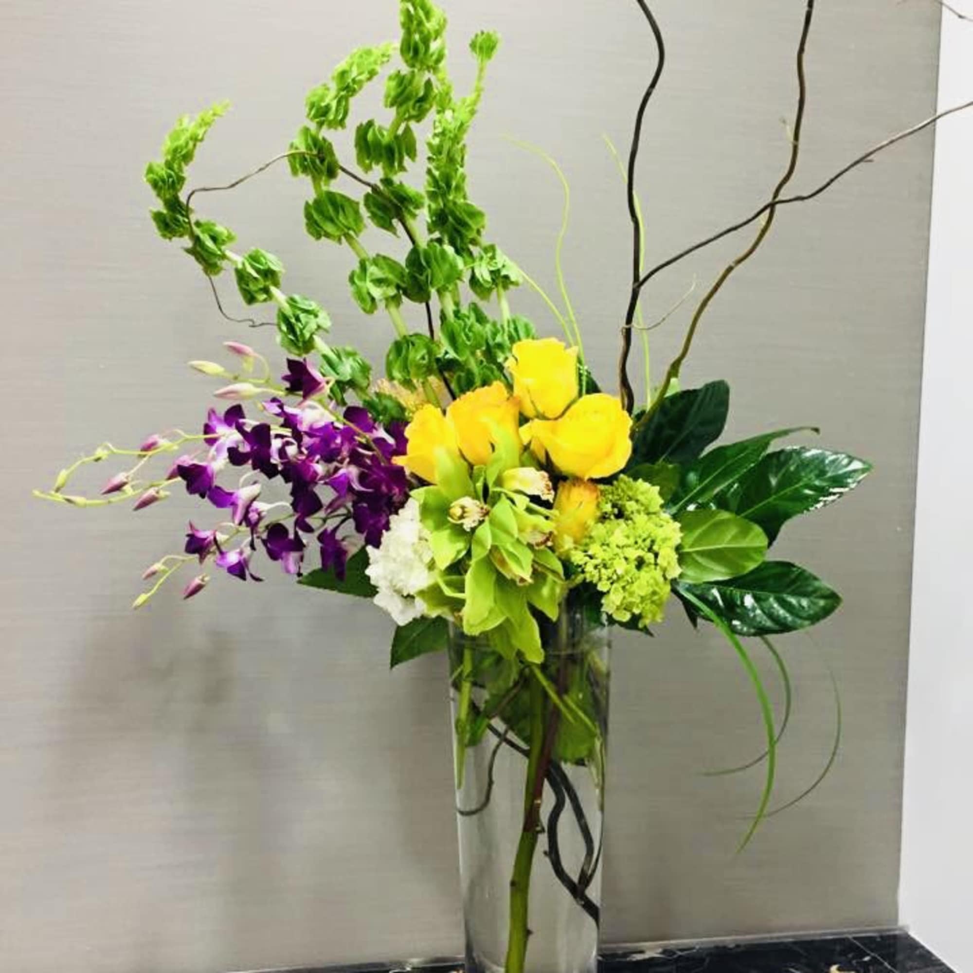 Sunlit yellow roses paired with vibrant purple orchids create a bold, celebratory