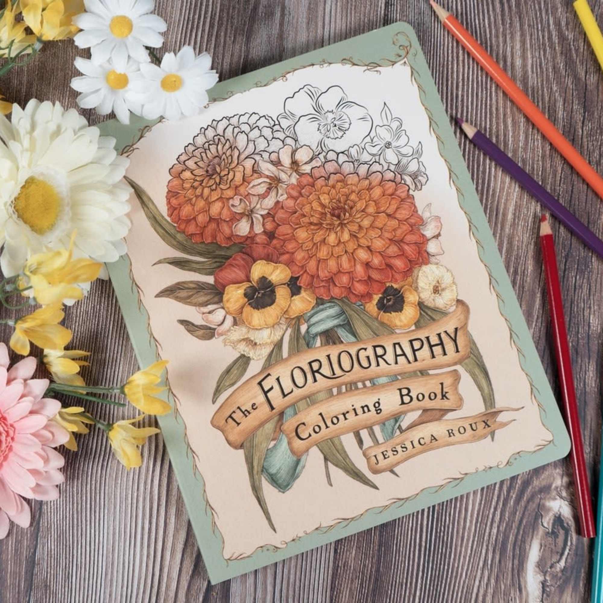 Coloring book with paper flowers and colored pencils on a wood surface