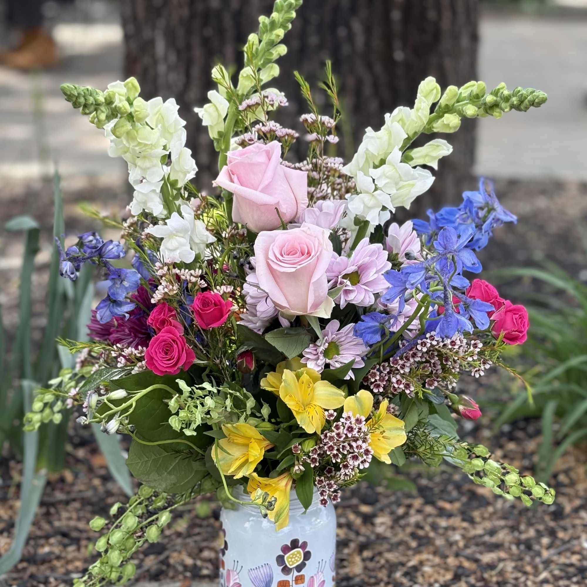 A cheerful, garden-style arrangement bursting with fresh spring color. Roses take center