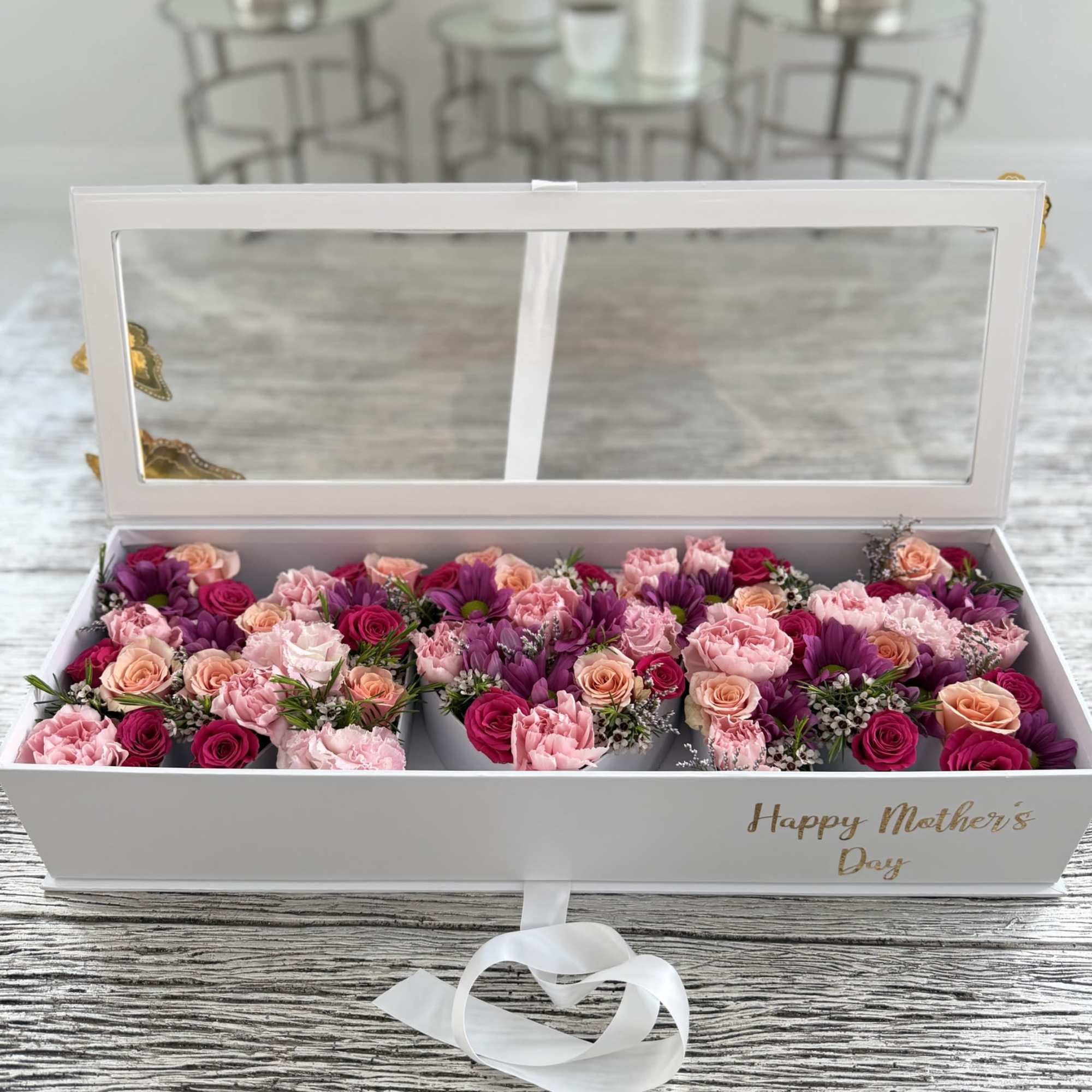 A long white gift box filled edge-to-edge with pink, peach, lavender, and