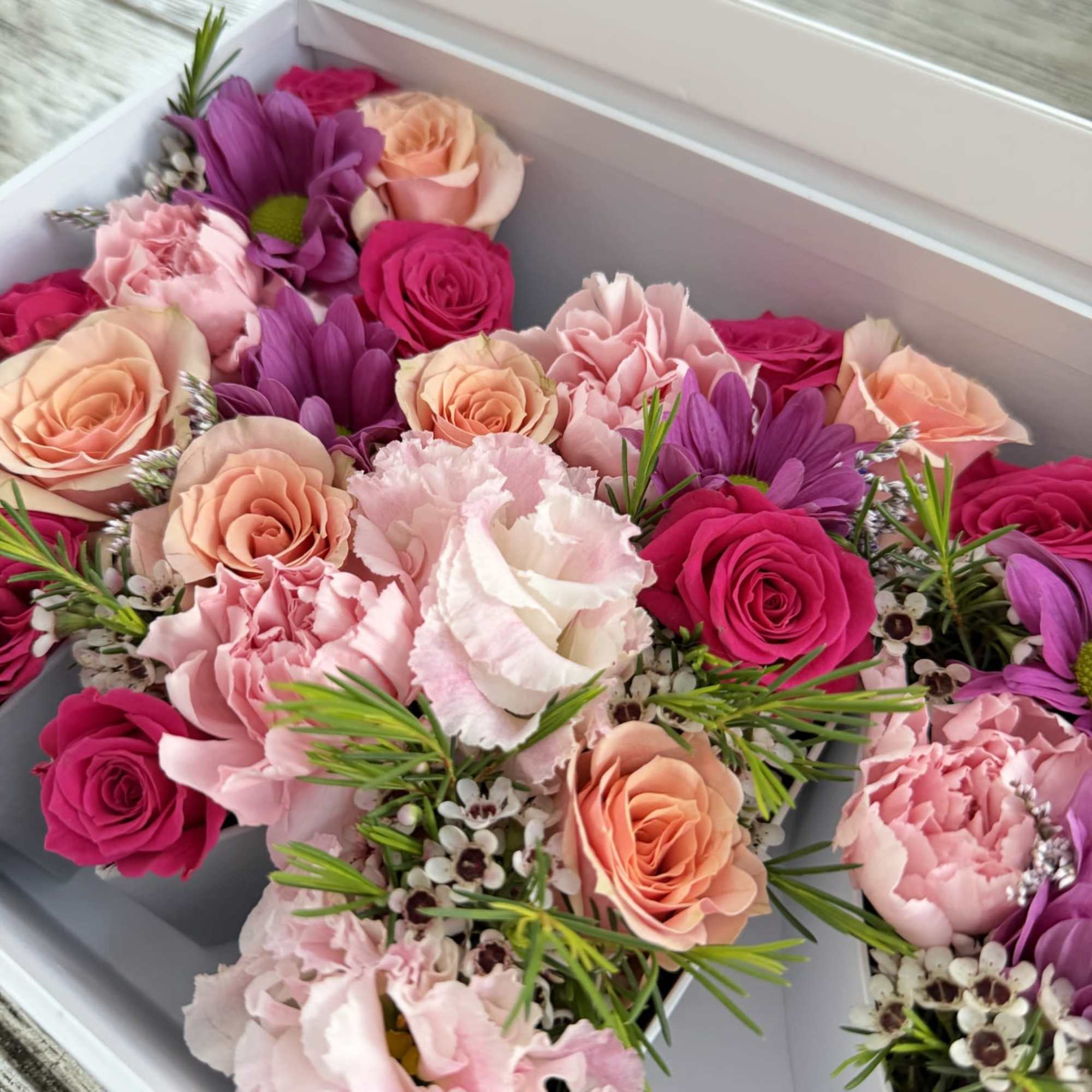 A long white gift box filled edge-to-edge with pink, peach, lavender, and