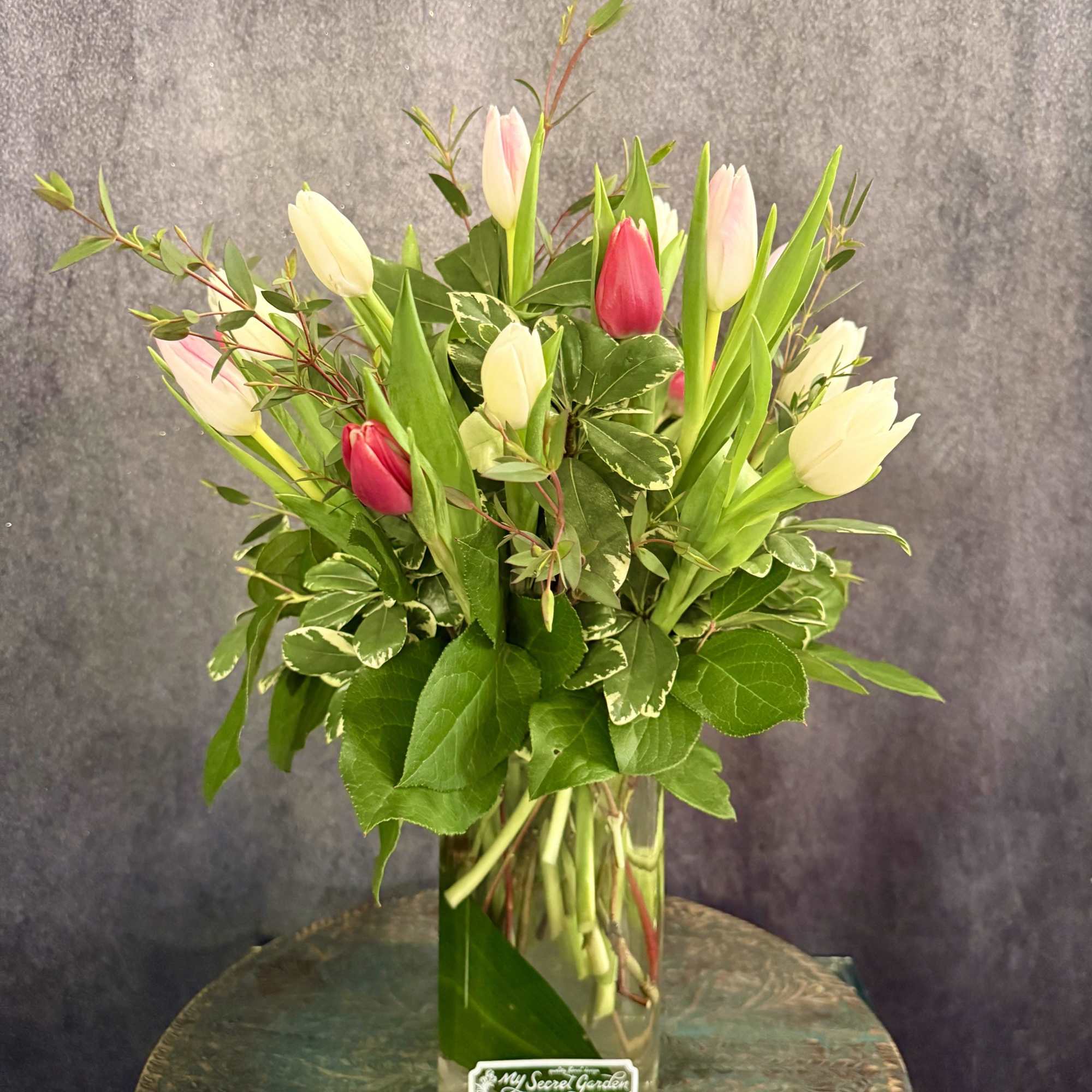 Pink and white tulips arranged in a clear glass vase