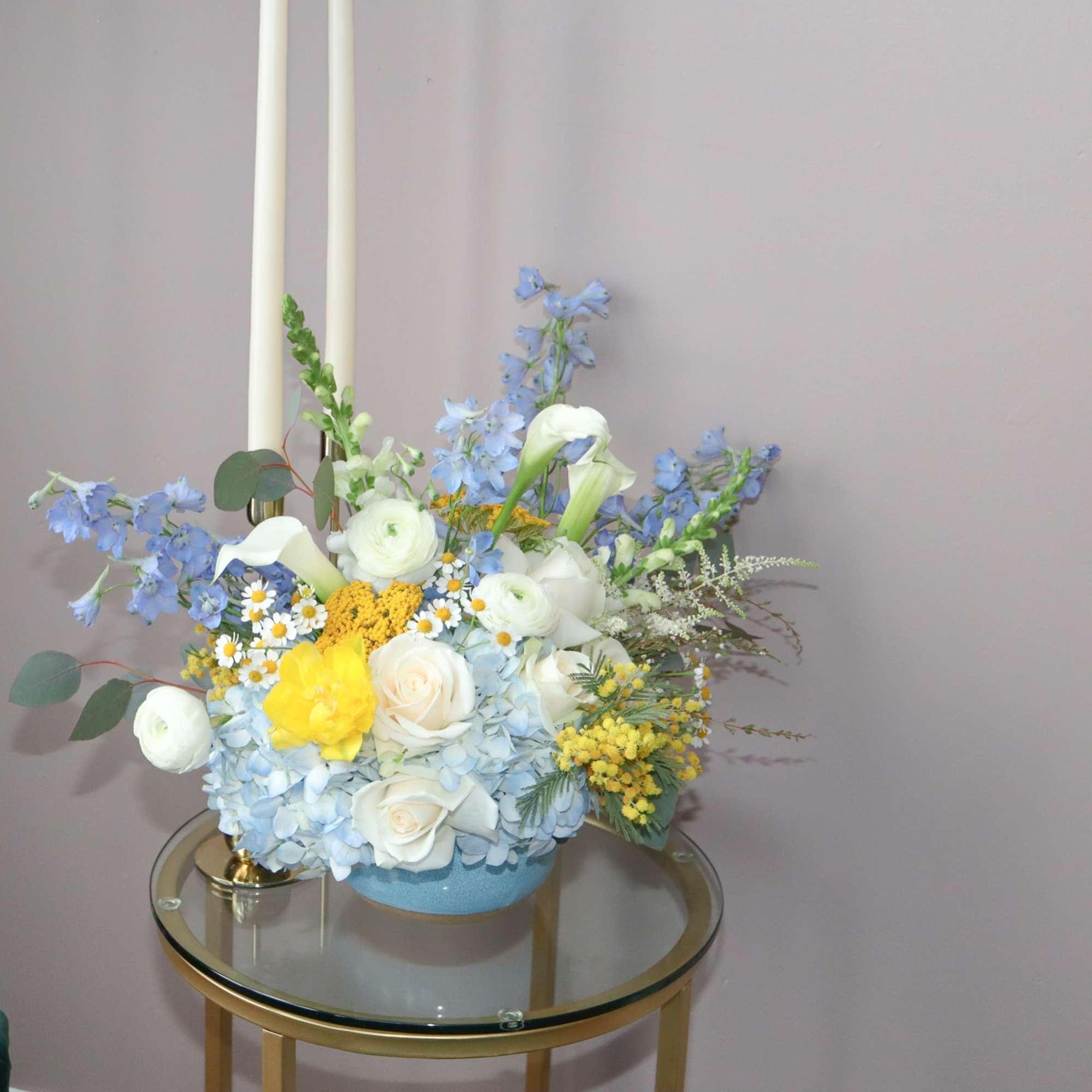 Blue and white floral arrangement with yellow accents in a low container