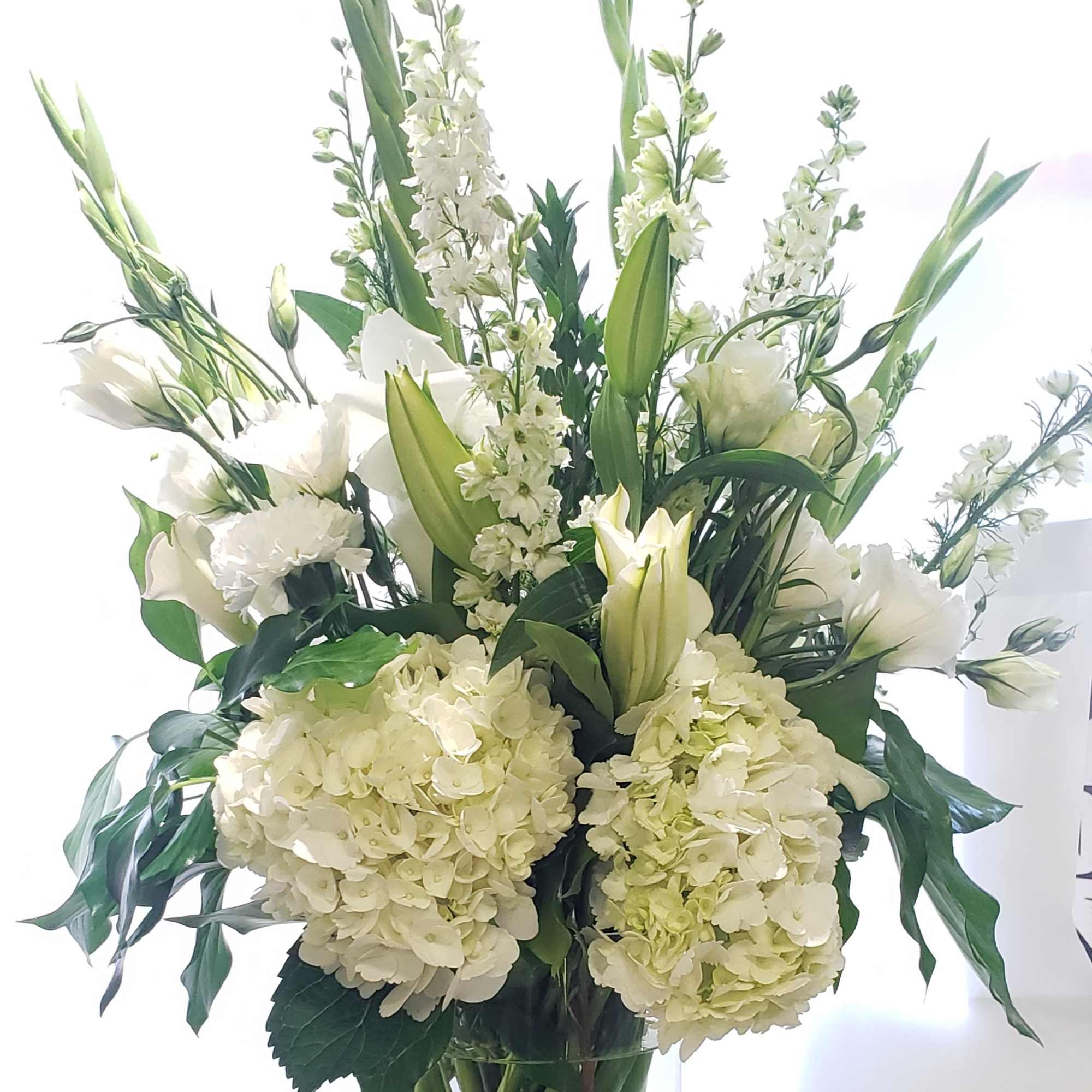 White floral arrangement in a clear glass vase with tall stems
