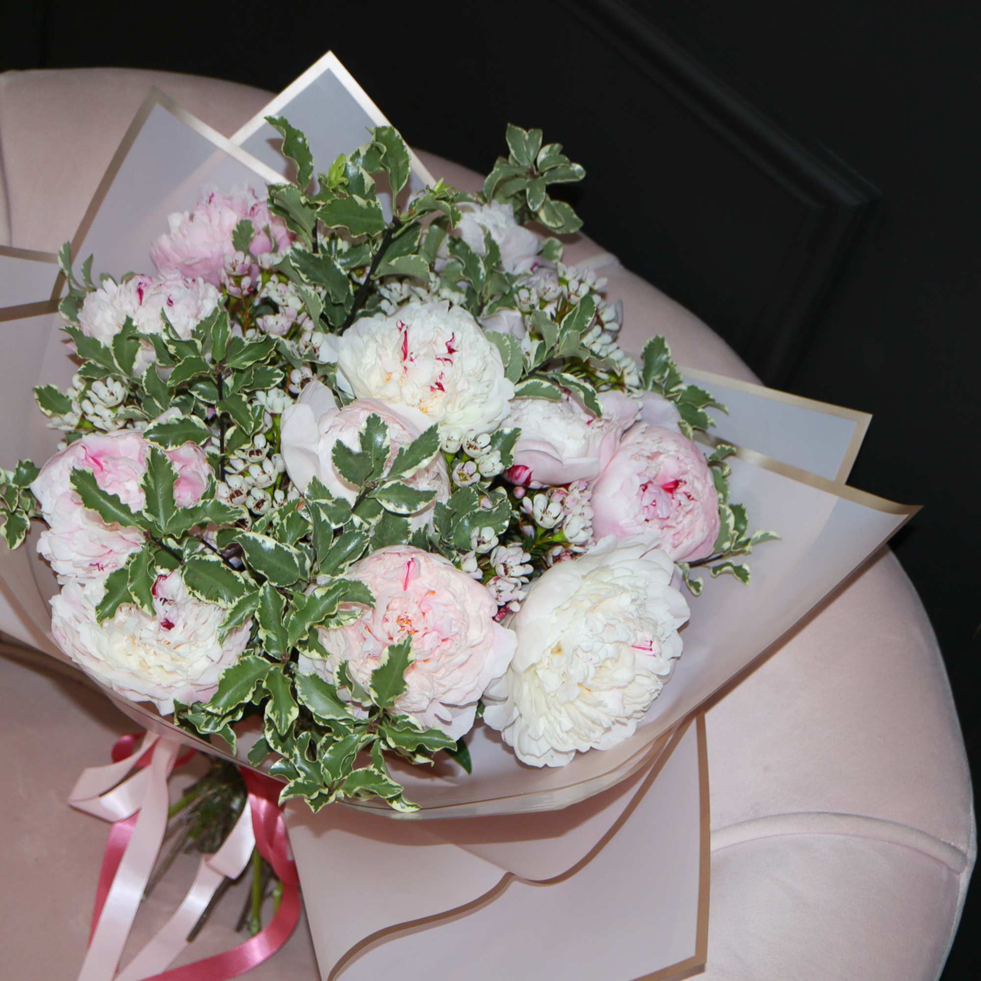 Bouquet of pale pink and white peonies wrapped in beige paper